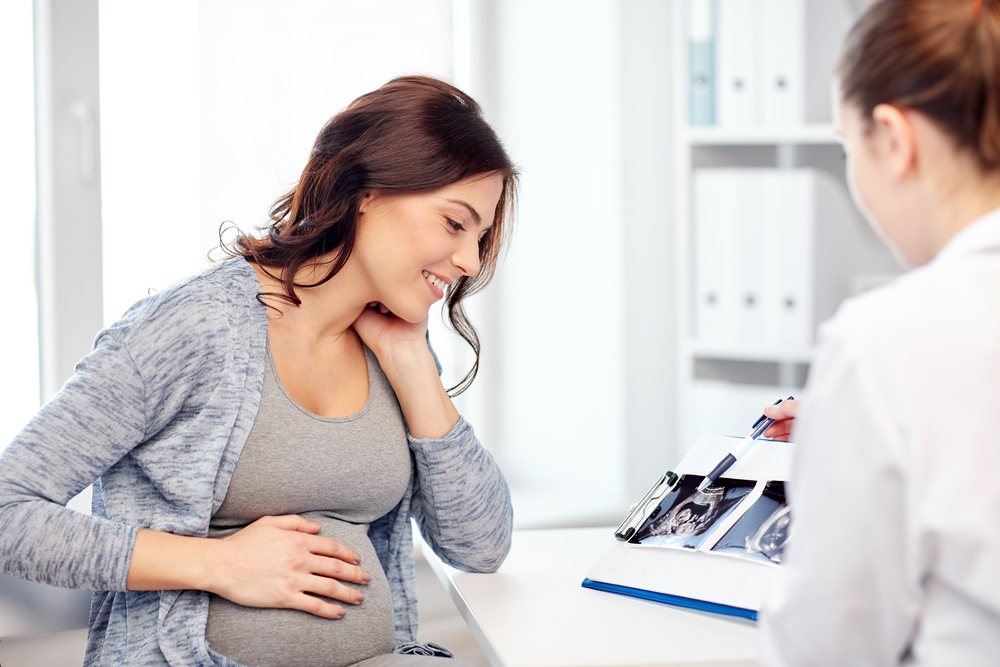 Pregnant woman during a prenatal checkup with her partner and an obstetrician