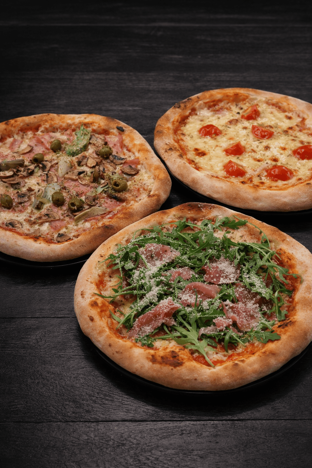 Overhead view of a kAlps Foodbar table spread with burgers, crispy fries, fondue dishes, a red cocktail, dipping sauces, and fresh garnishes arranged on slate serving boards.