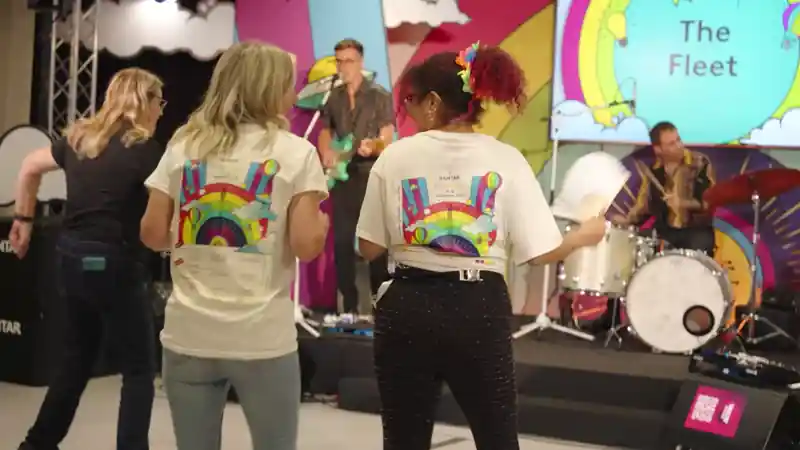 Group of presenters speaking on camera during a Microsoft live broadcast, filmed against branded event graphics.