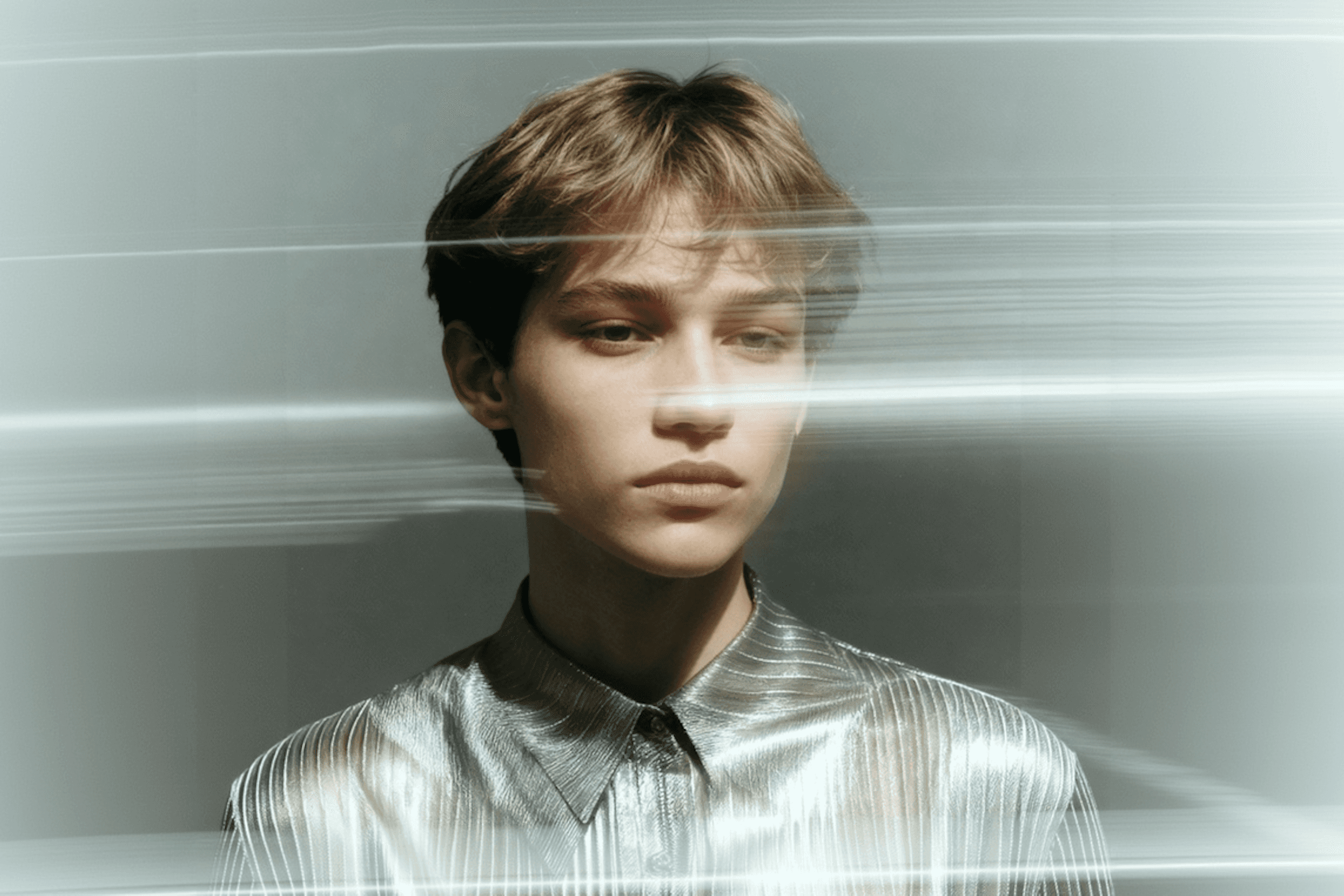 A portrait of a person in a metallic shirt with a streak of light crossing the frame, creating a modern and artistic vibe.