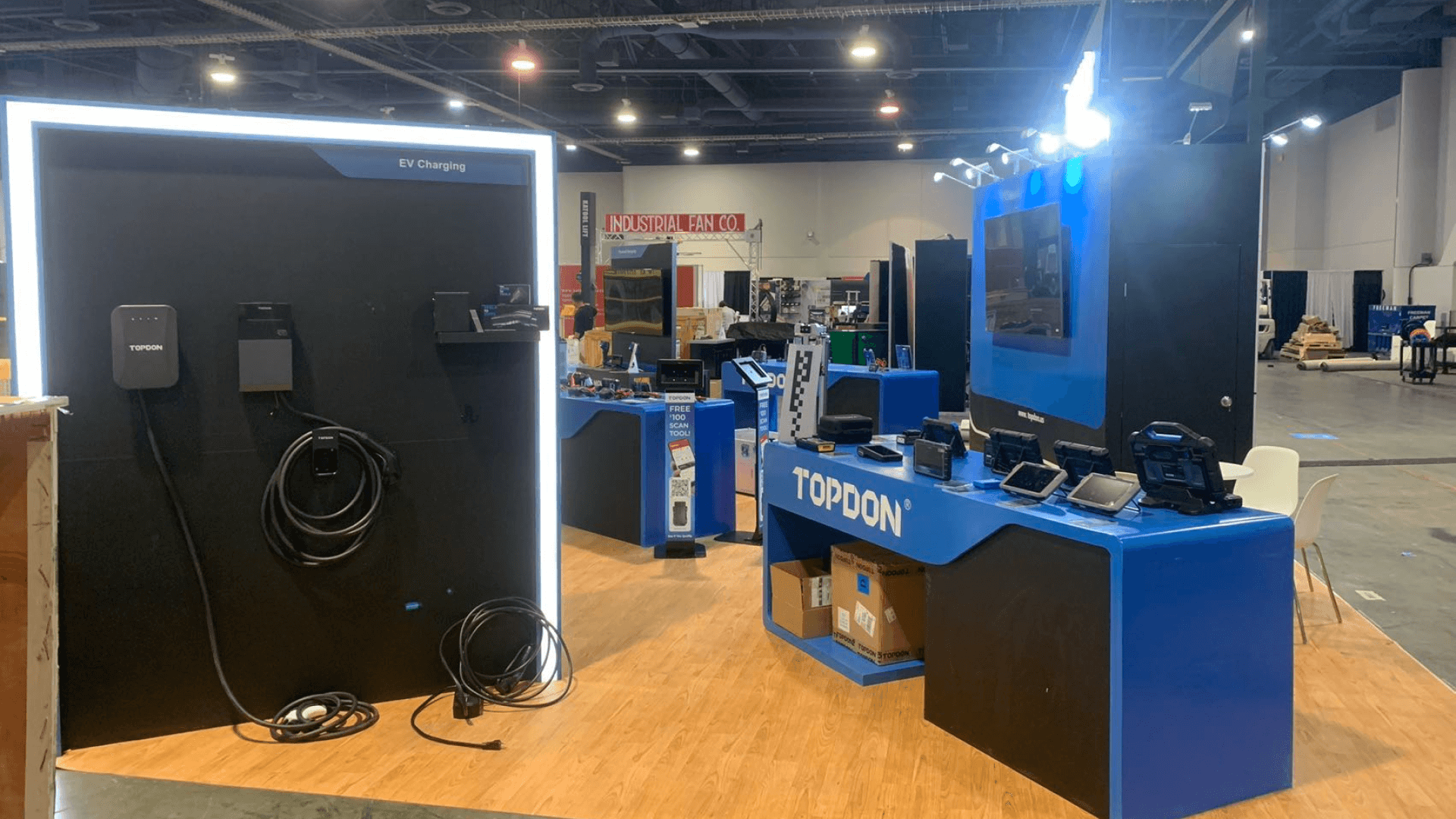 Automotive product demo booth with sample handling area, display counters, product screens, storage, and staff presentation space