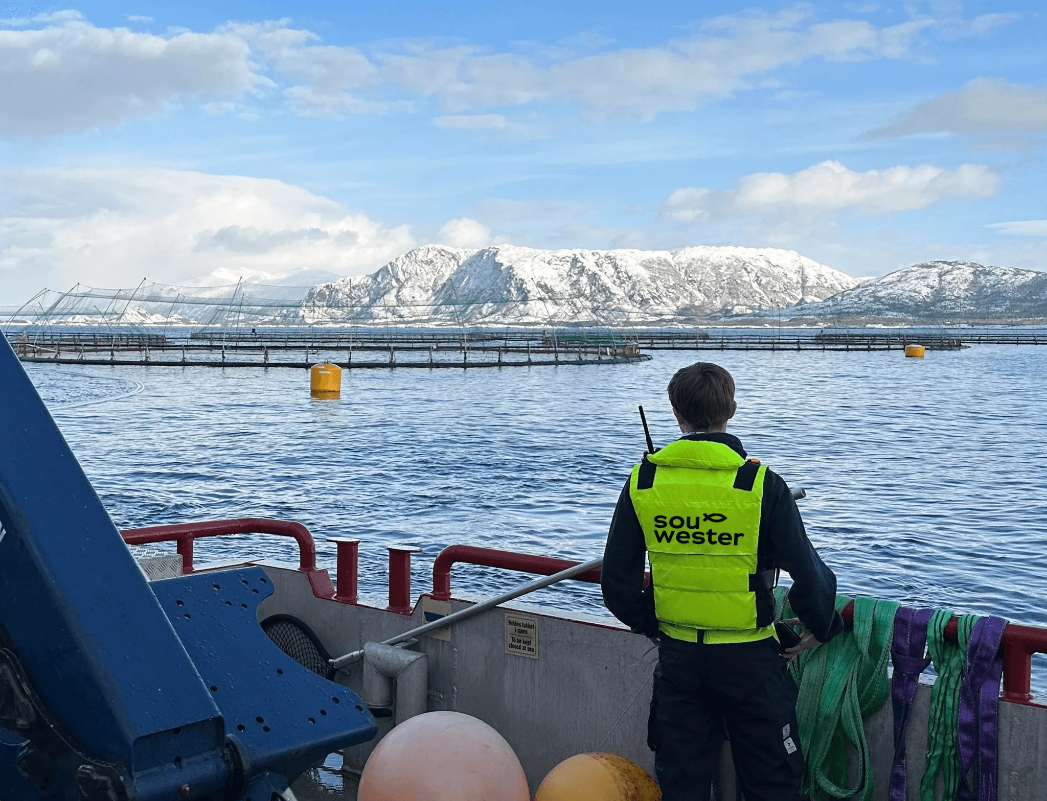 souwester ansatt med redningsvest på, hen ser utover anlegget på havet fra arbeidsbåt