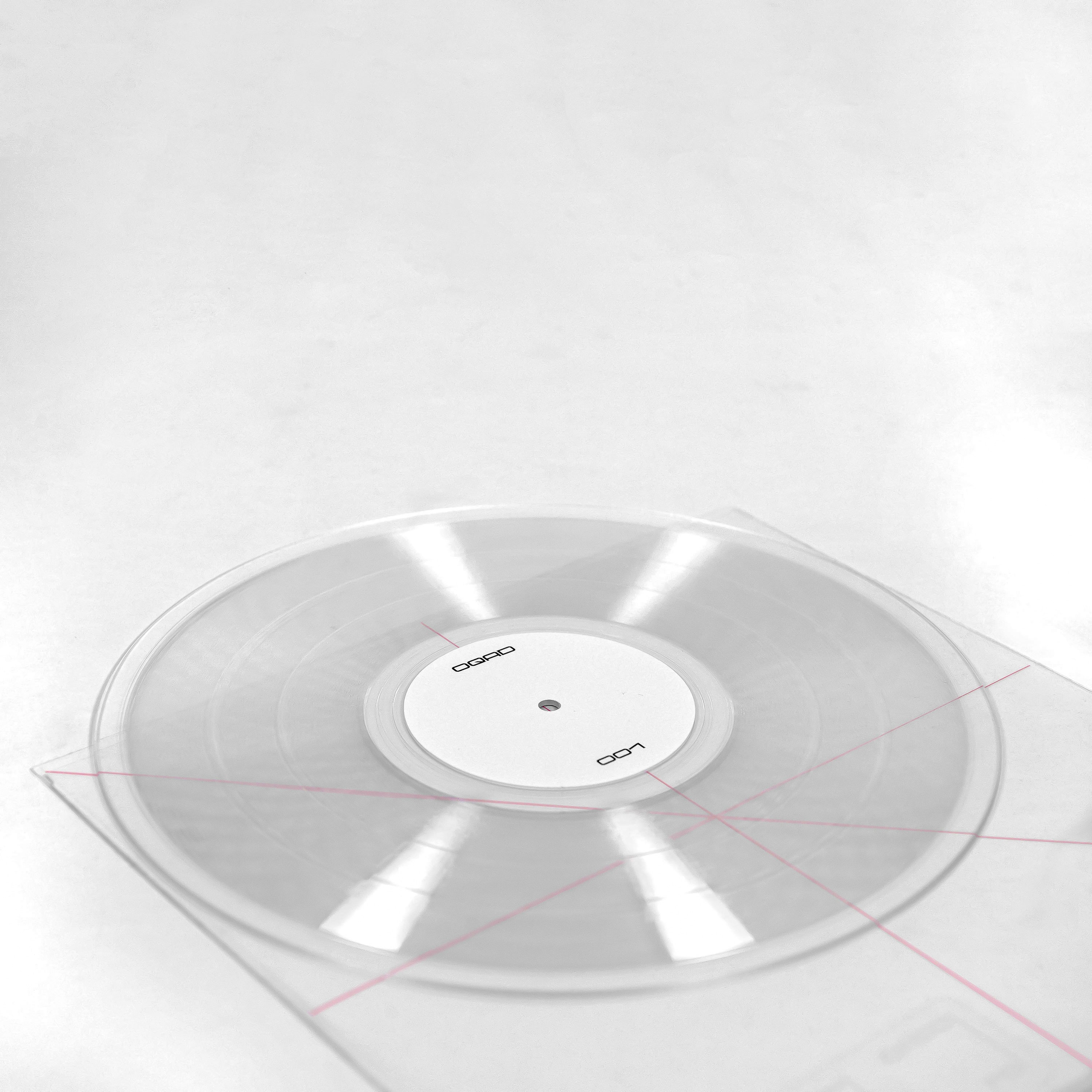 Angled view of a clear transparent OQAD 001 vinyl with white centre label and thin red guide lines