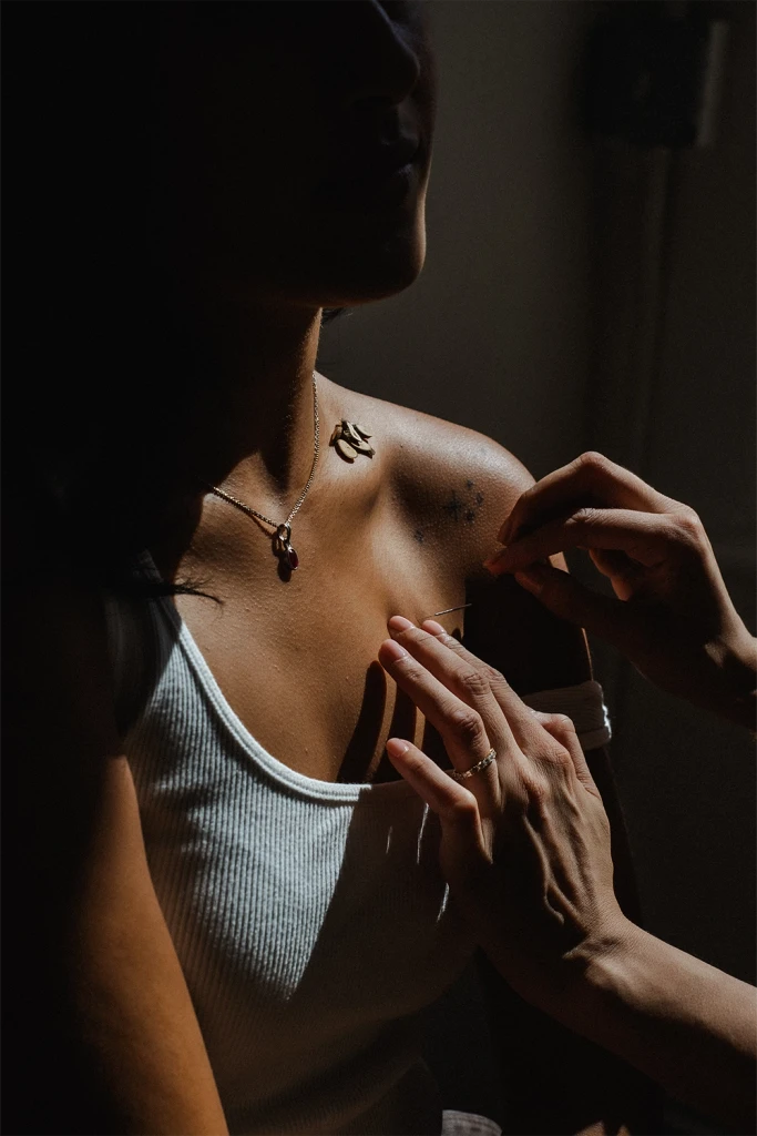 A practitioner's hands resting gently on a client's shoulder in soft shadow