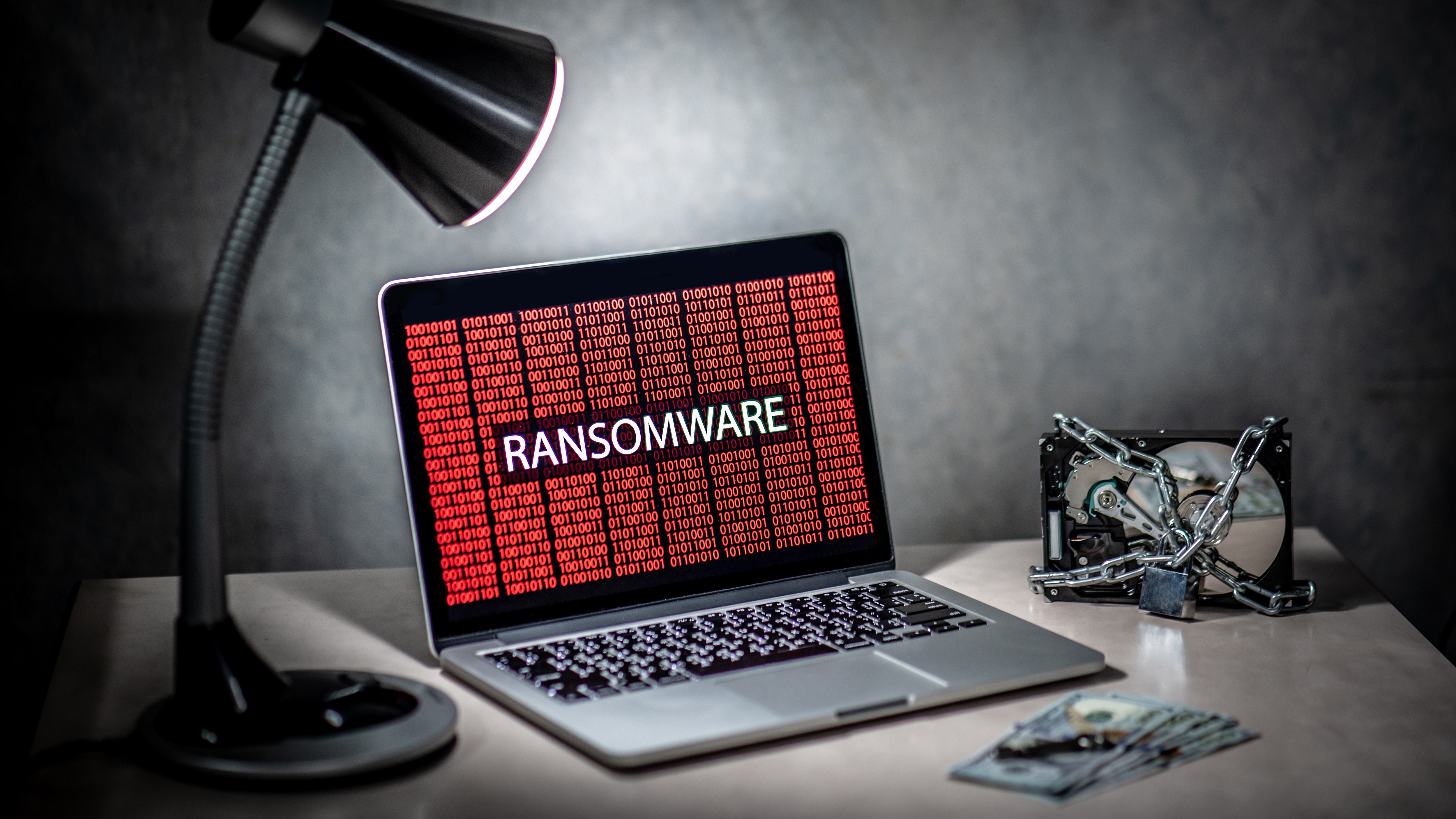 Hard disk file locked by chain and padlock with laptop computer monitor show red binary ransomware