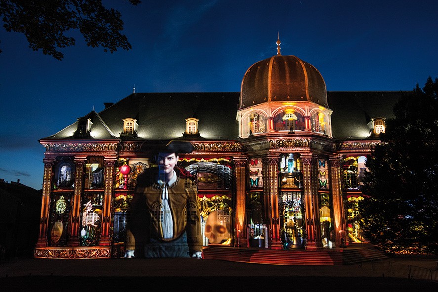 Group of people gathered around a wooden table with laptops, shaking hands during a team meeting.