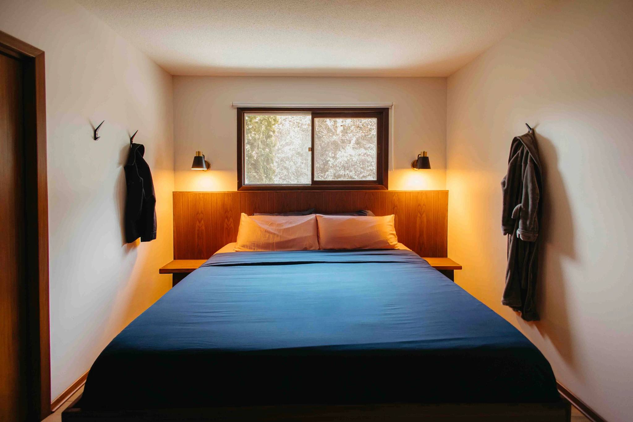 A bedroom after renovation with custom headboard and floating lighting