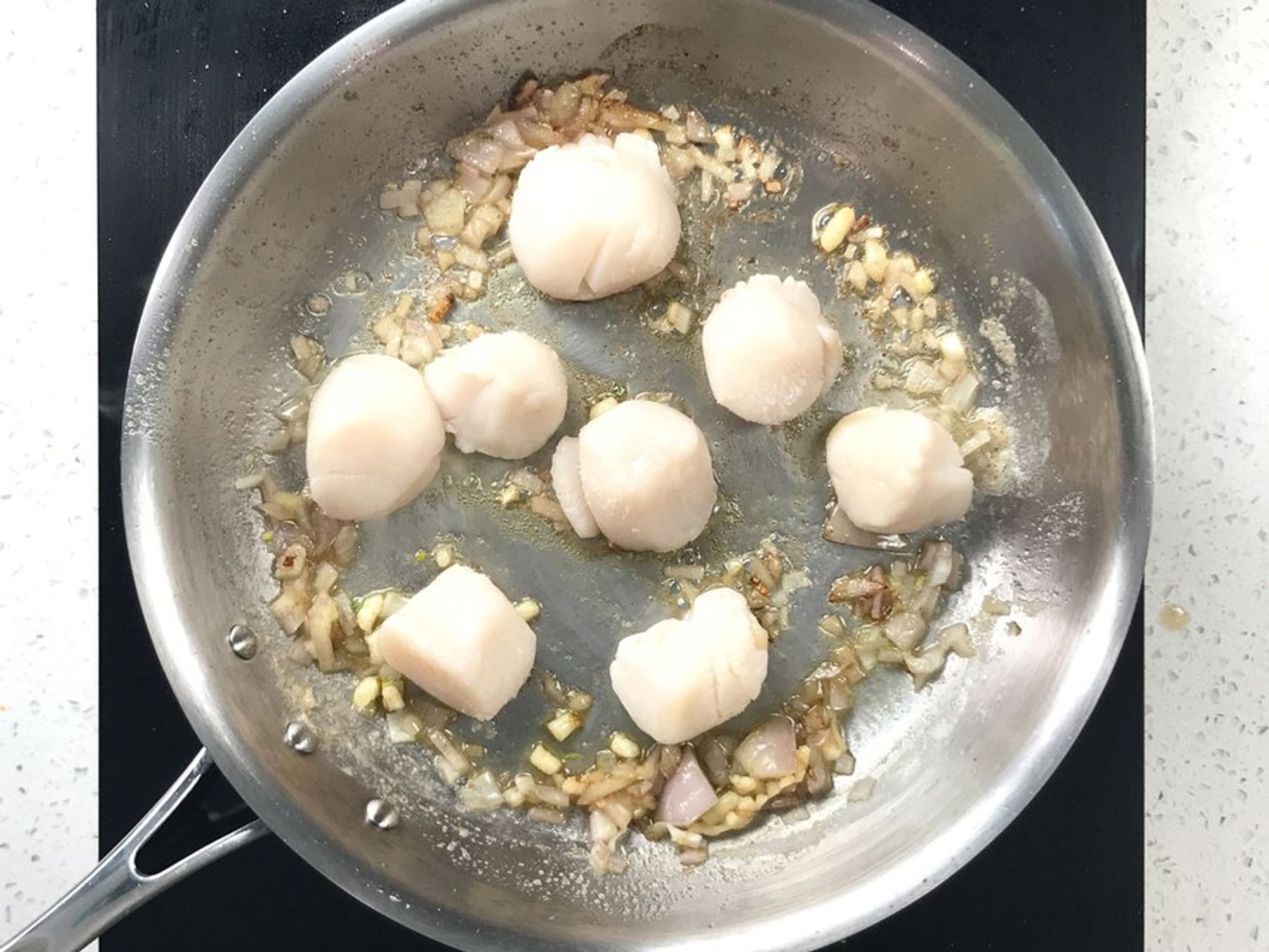 scallops in a pan with shallots and garlic