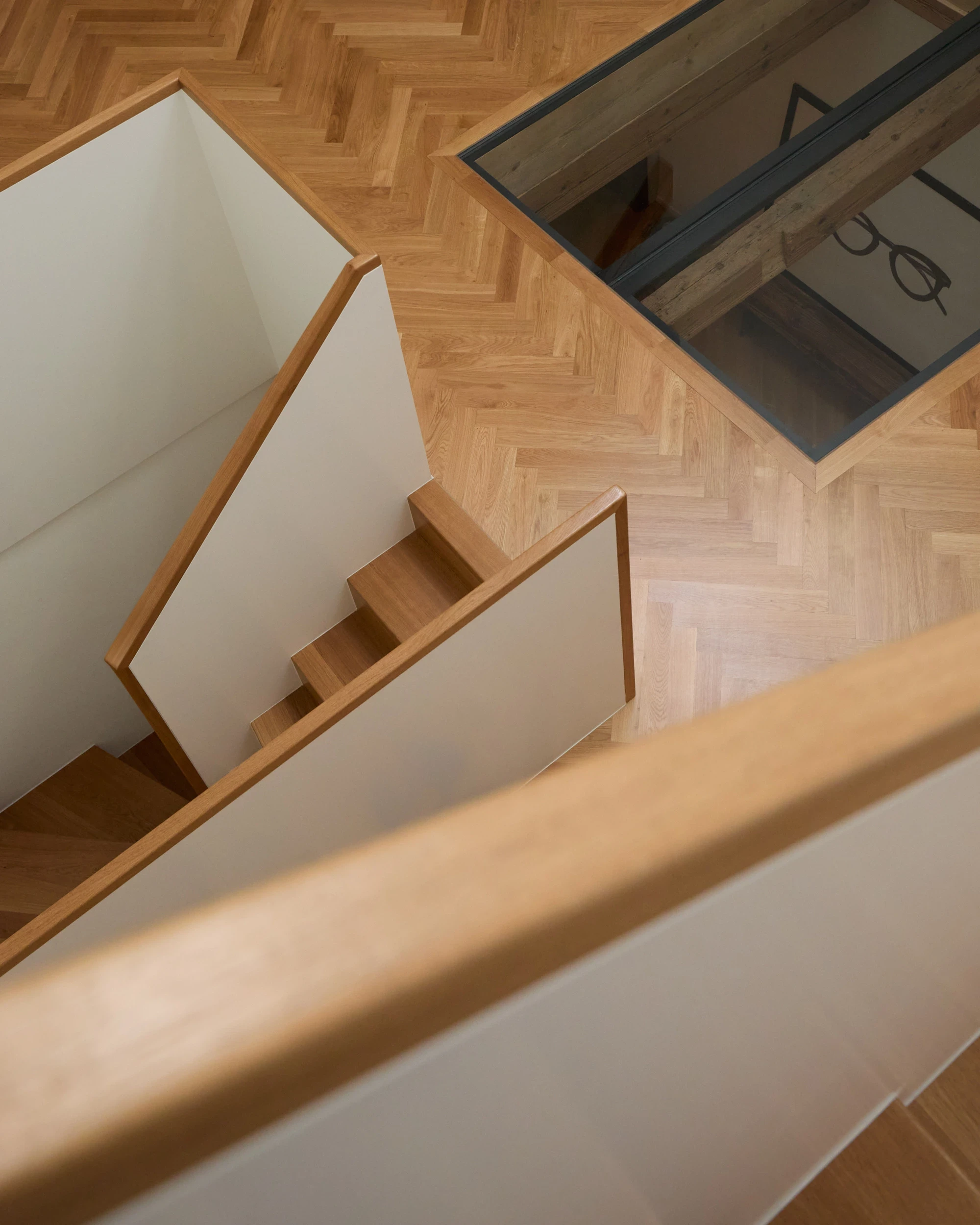 Détail de l’escalier intérieur en chêne de la maison Muriset à Cully, avec vue sur le puits de lumière, intervention contemporaine dans un bâtiment historique du Lavaux.
