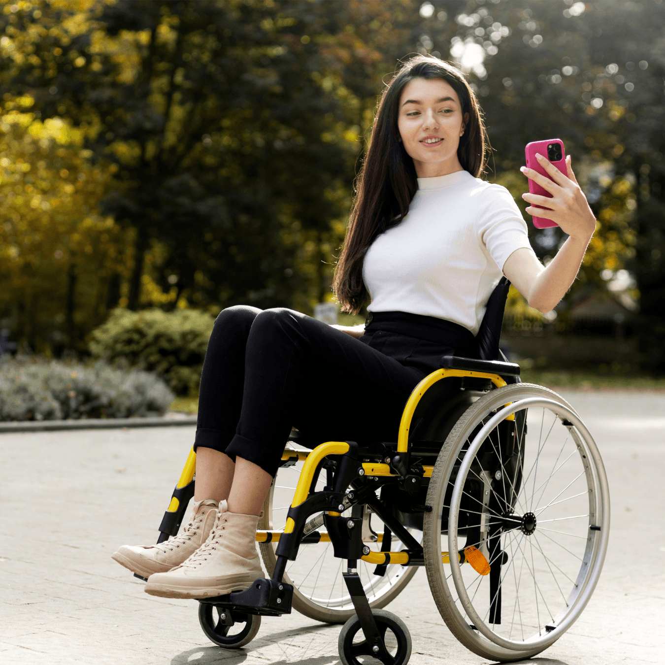 A woman in a wheelchare holding her phone in front of a cafe