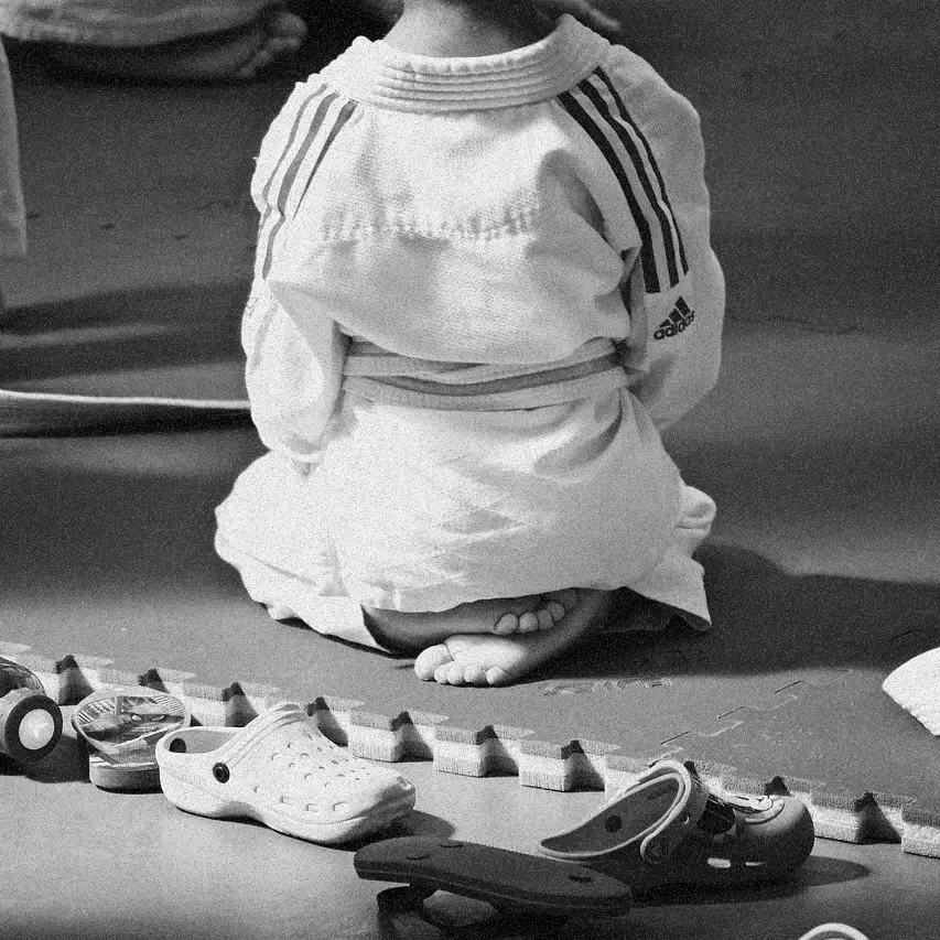 Judoka in a white gi kneeling on the mat.