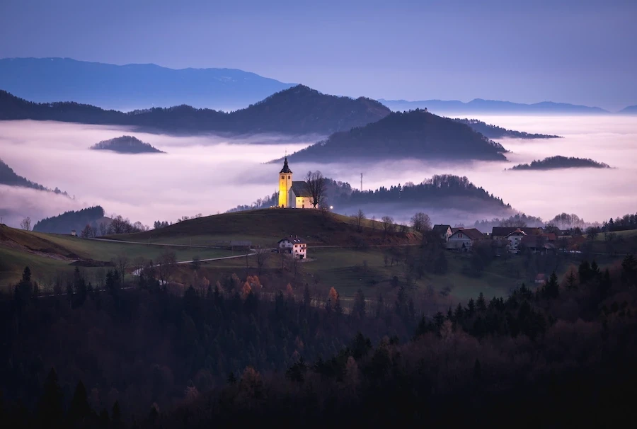 A foggy morning view of Sveti Andrej church and surrounding countryside of Slovenia.