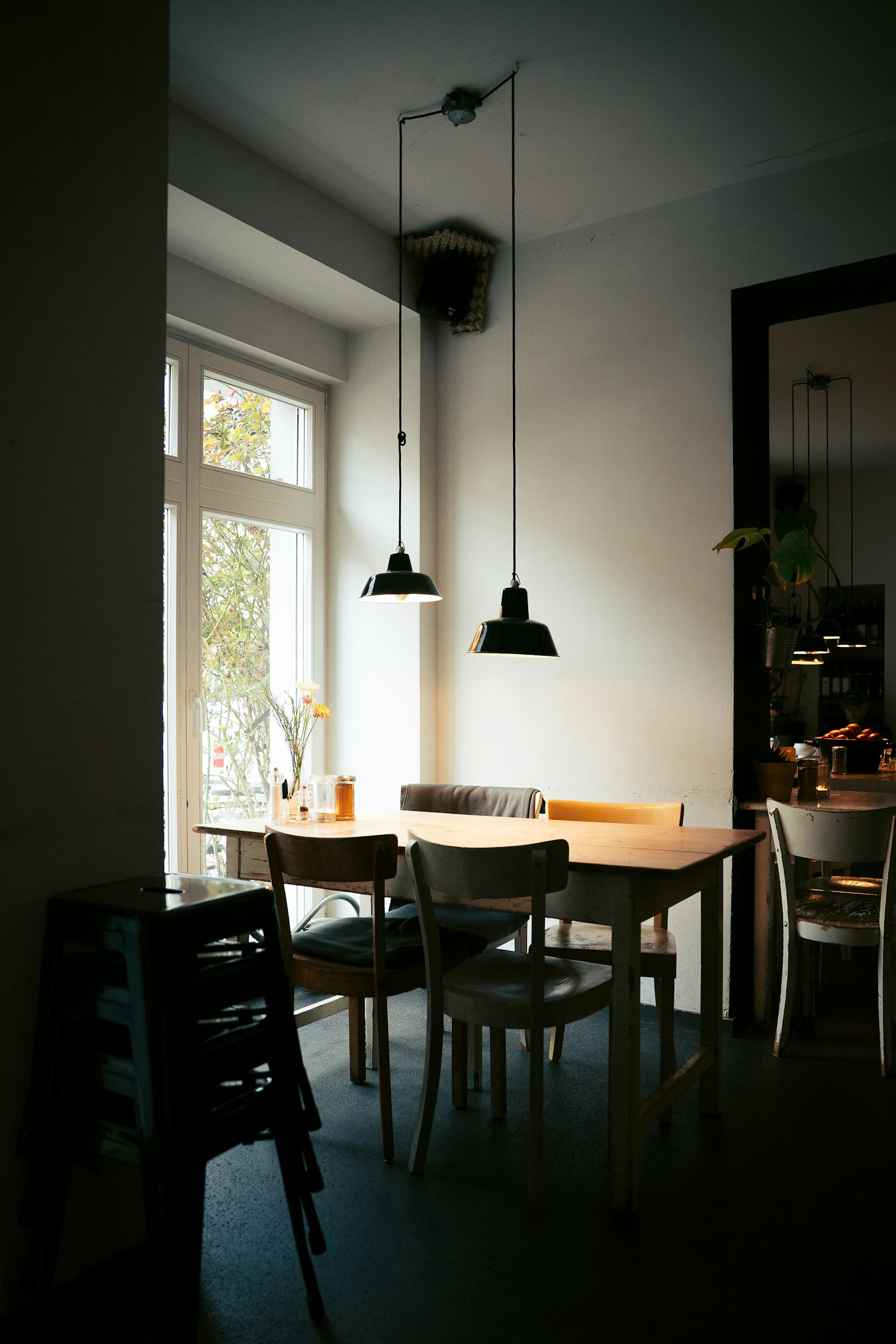 Interior de café con mesas de madera y grandes ventanales de luz natural