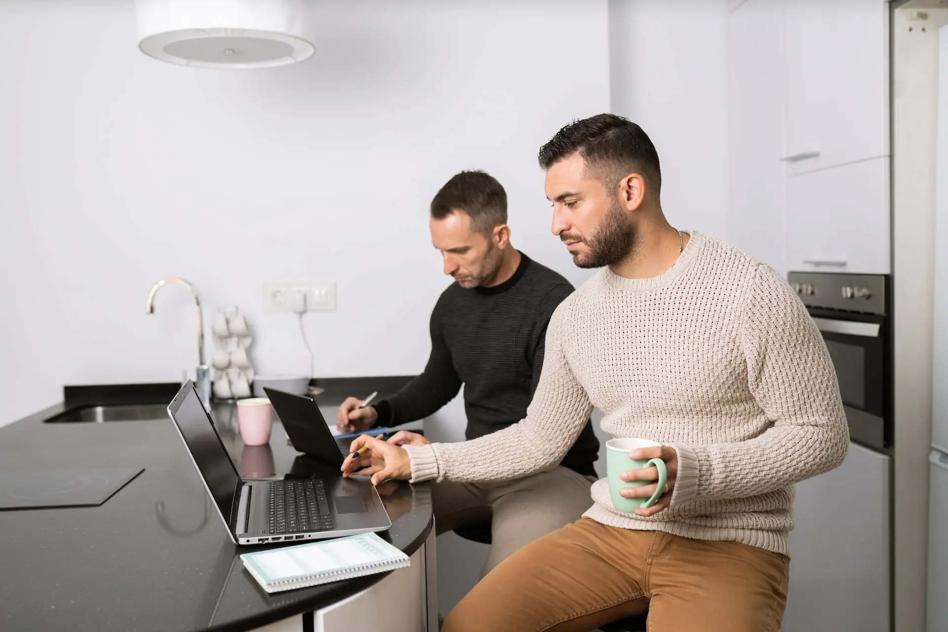 Twee mannen werken samen aan laptops in een moderne kantoorruimte.