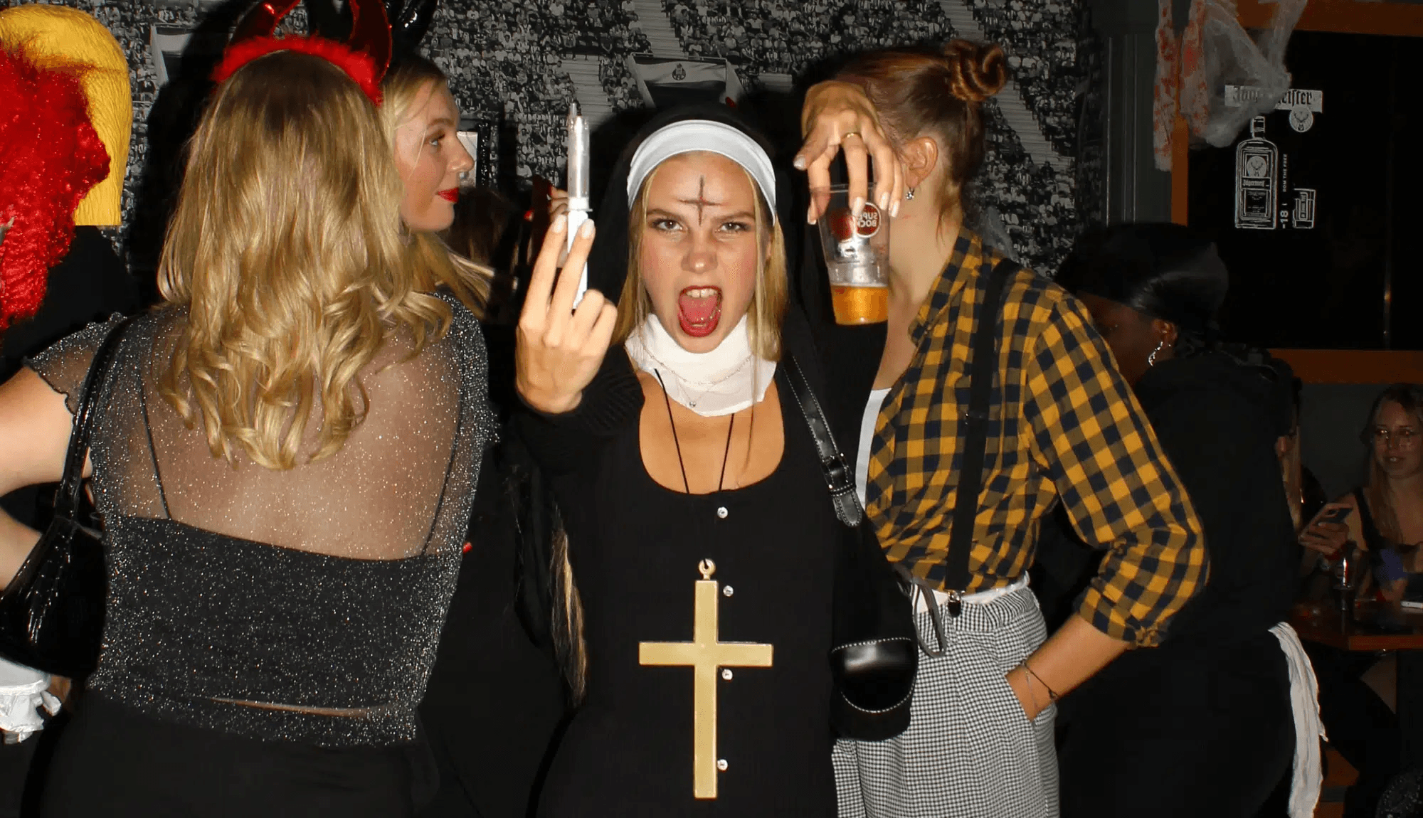 Halloween pub crawl participants in nun and devil costumes inside a bar