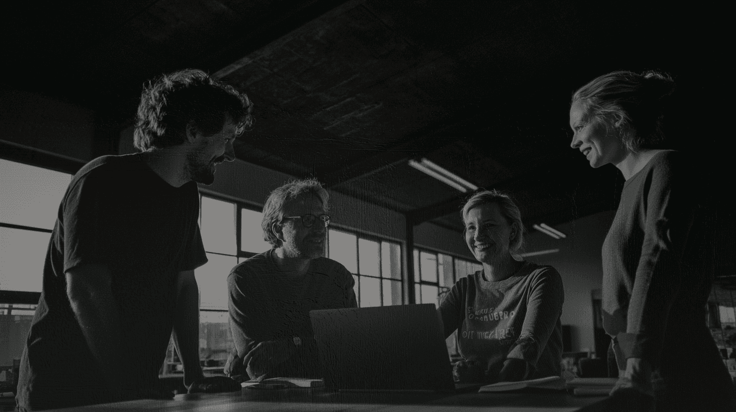 Black and white image of team of 4 people discussing some project