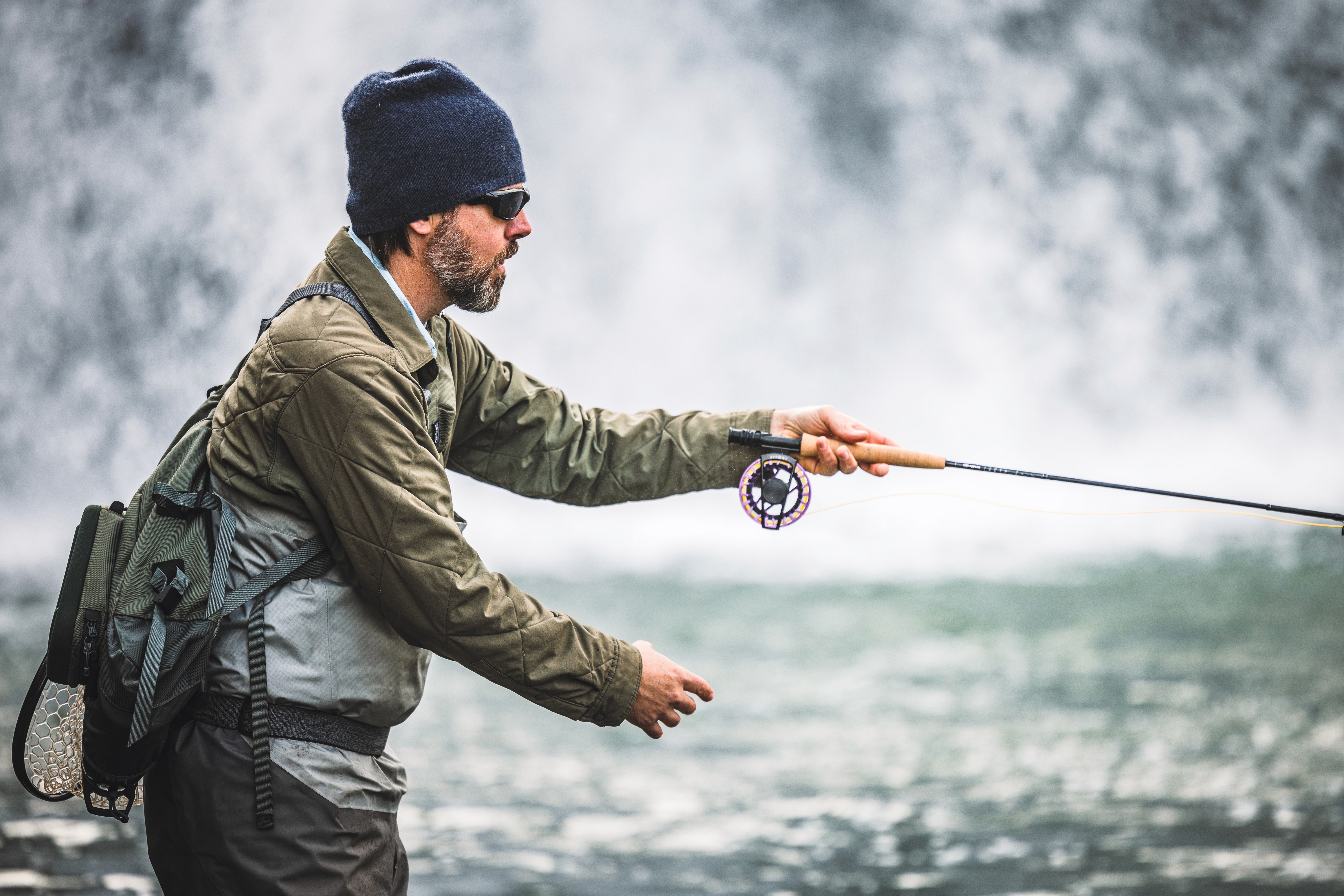 man fly fishing in the winter near waterfall