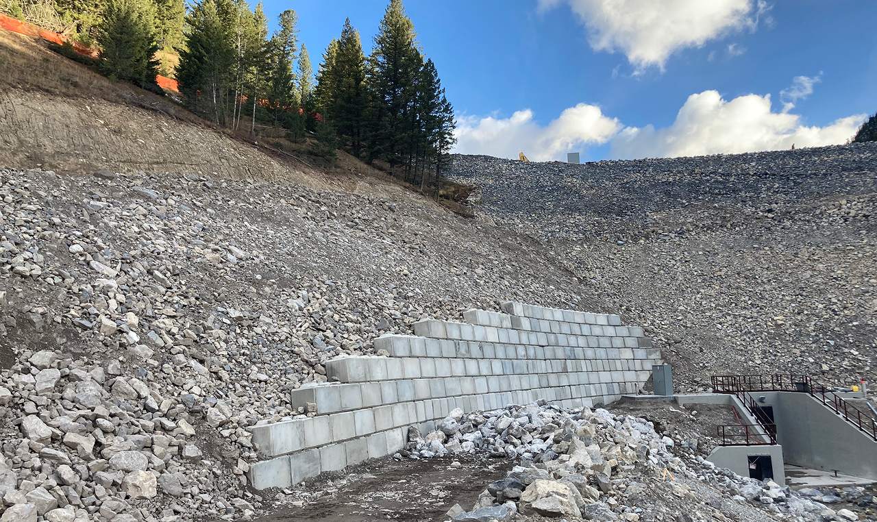 Lock block retaining wall construction with blast rock backfill supporting steep access road at Cougar Creek Dam