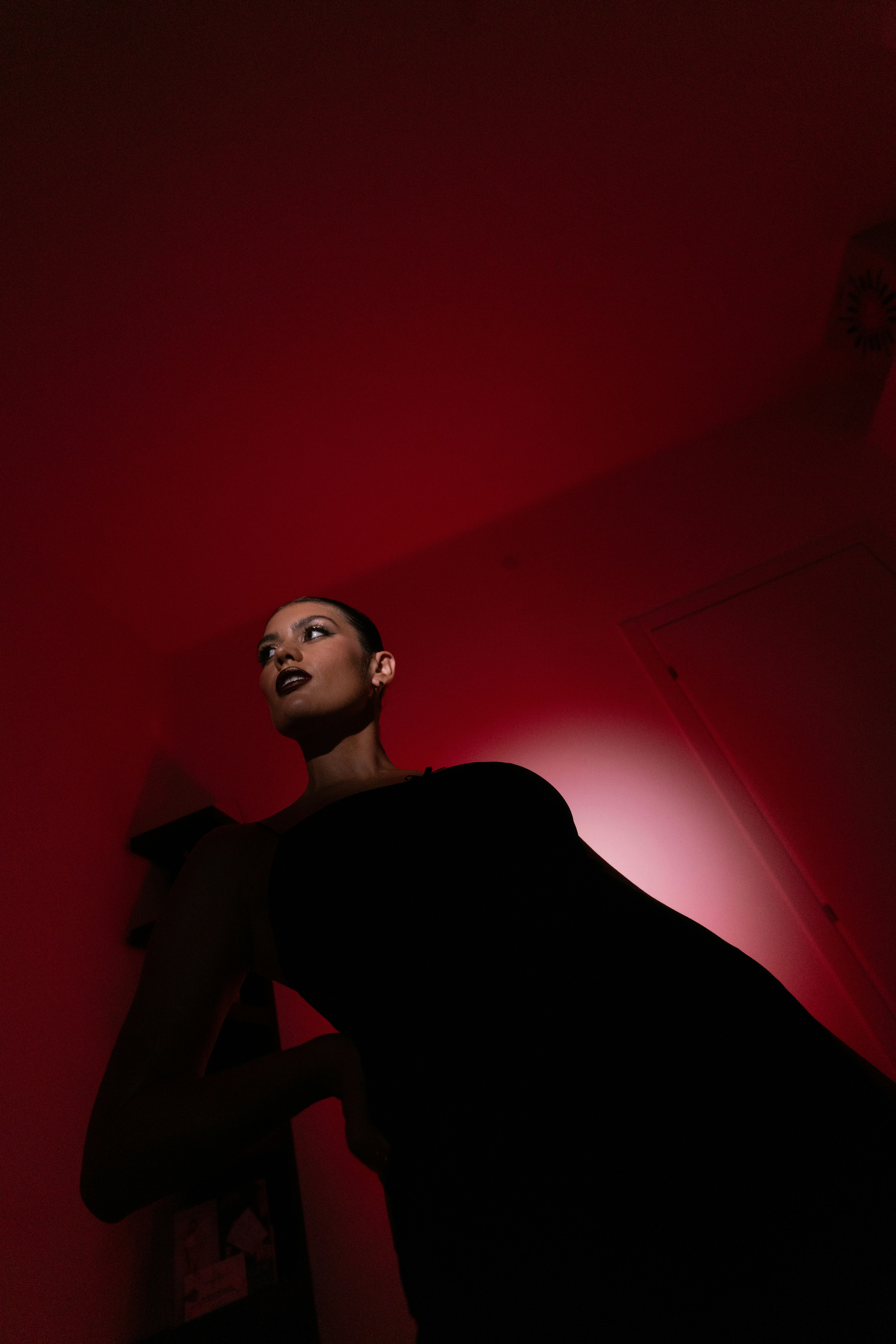 Woman in black dress under red light