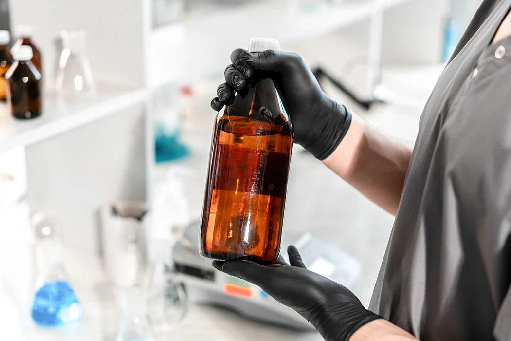 Woman in a lab holding a bottle containing a liquid chemical