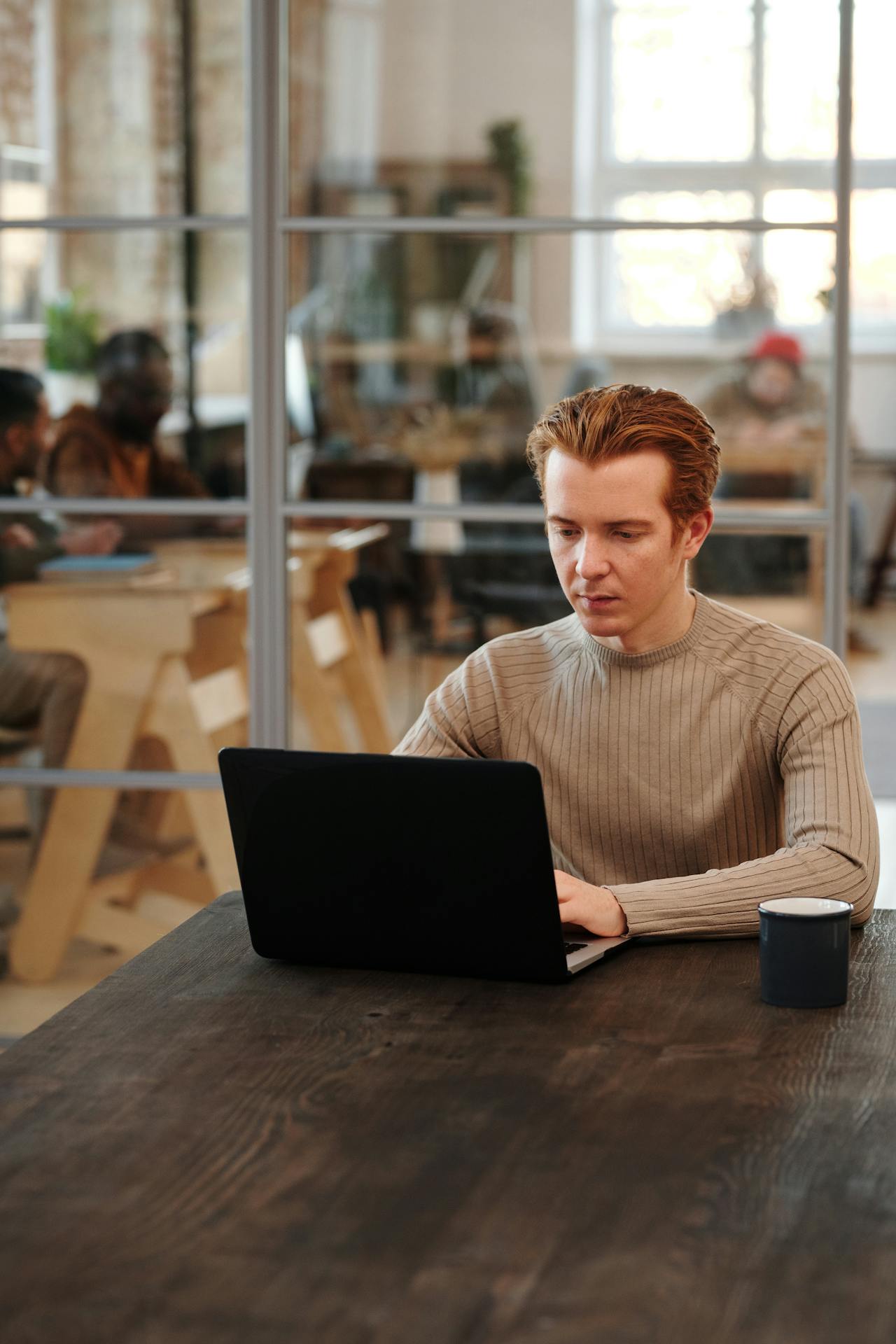 Man in a modern office space working on a laptop, showcasing focus and productivity