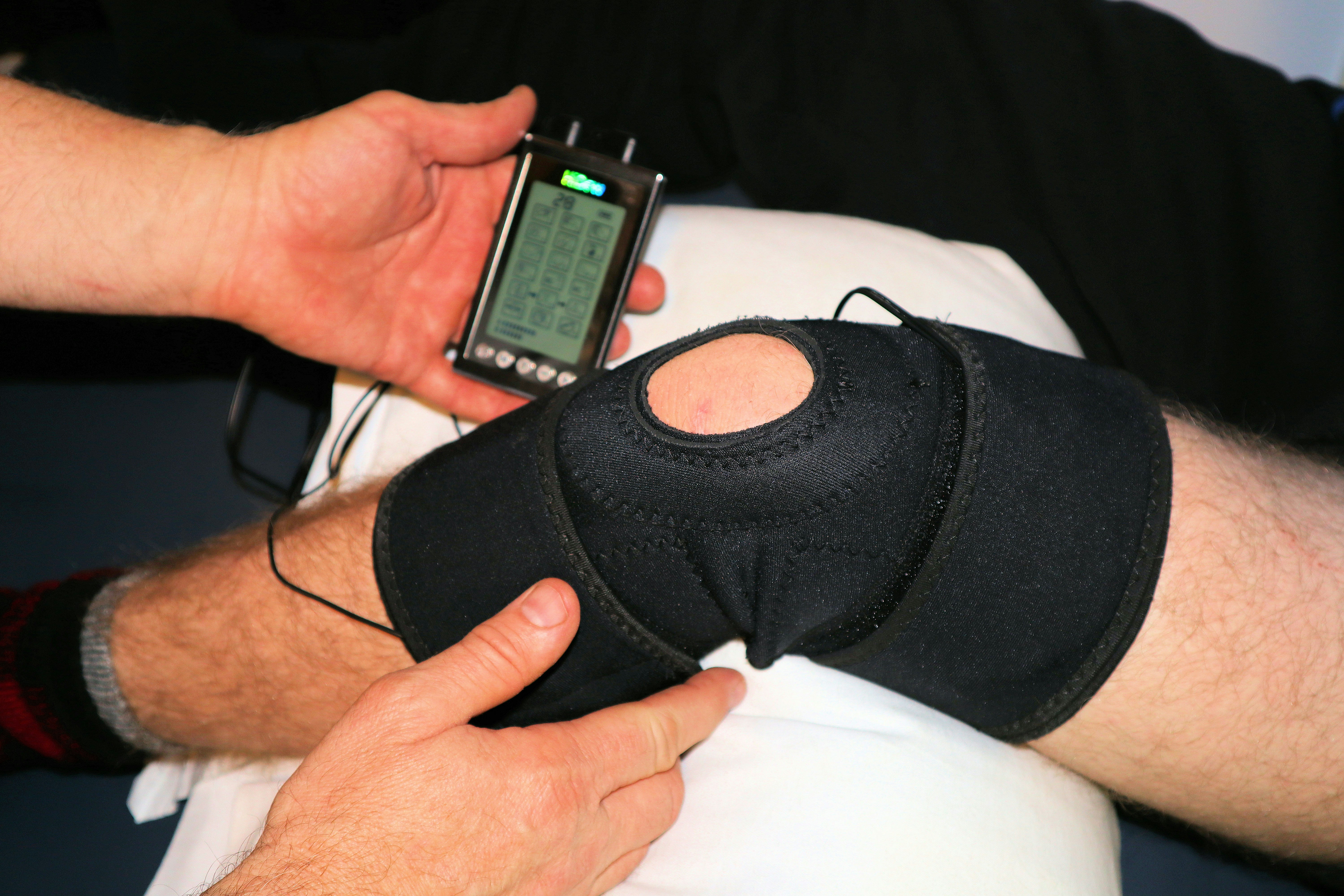 Doctor looking a patients leg which is using heat and vibration to resolve ACL injuries