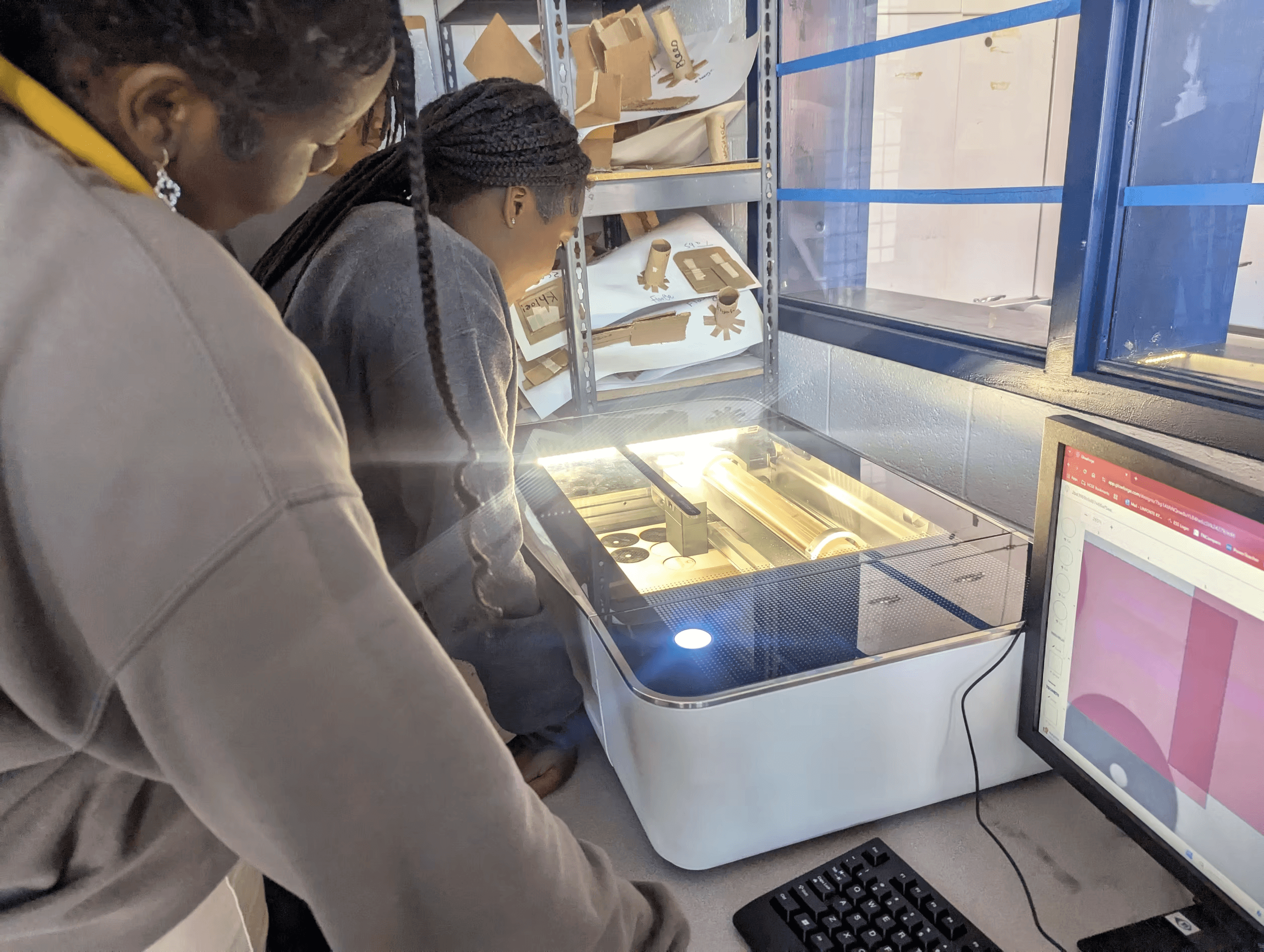 Students gathered around a glowforge machine.