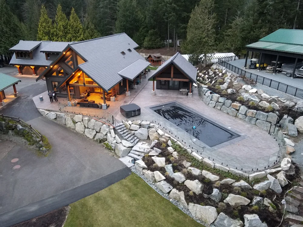 Commercial glass railings installed around a luxury lodge patio and outdoor pool area, featuring clear glass panels and modern hardware integrated into a landscaped hillside property.