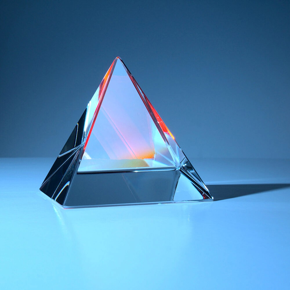 A glass prism refracting light against a blue background