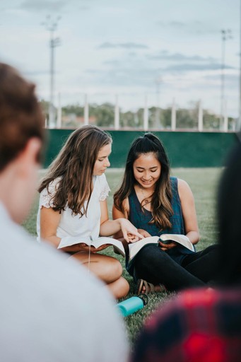 a group of people sitting on the ground looking at a book