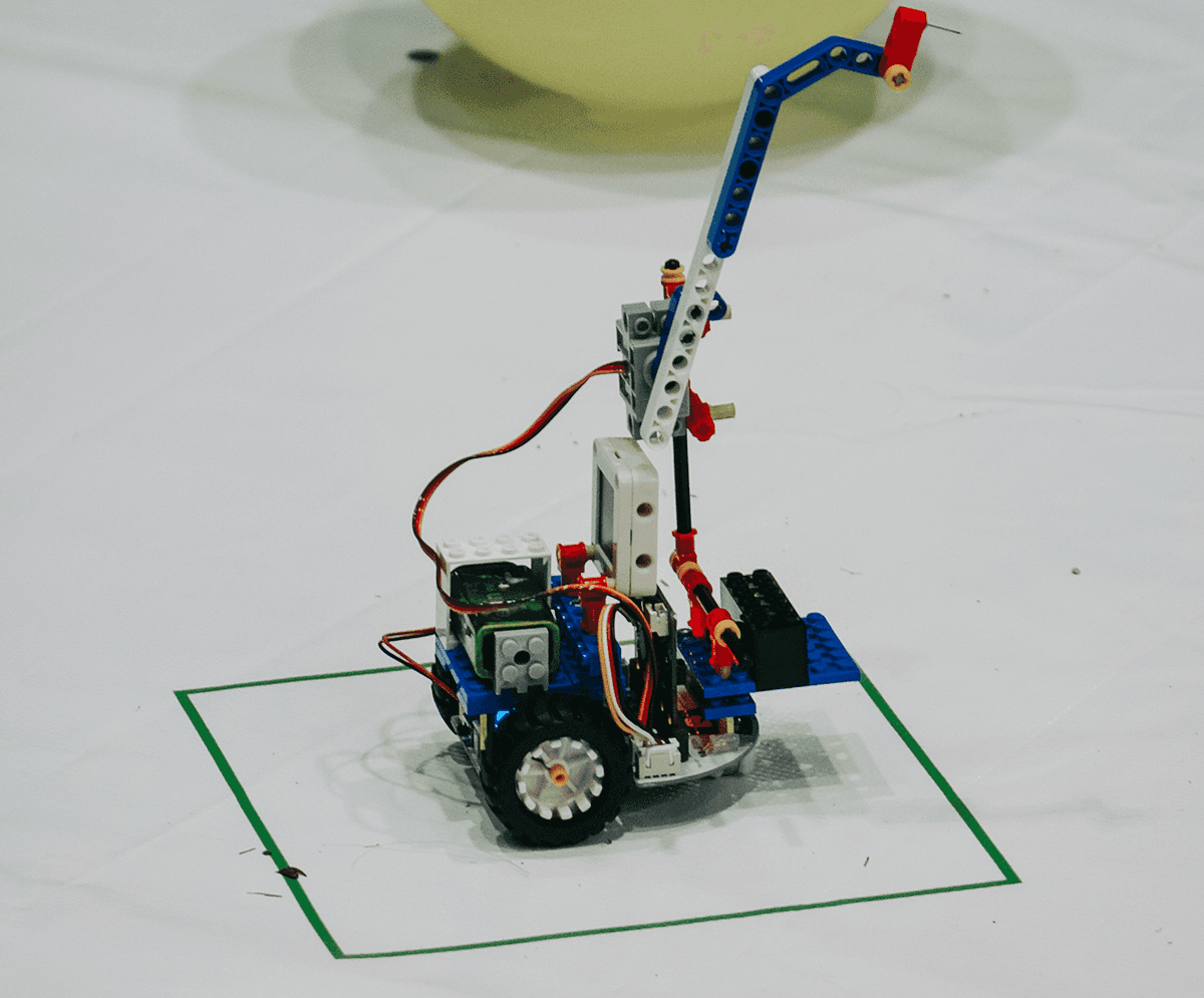 Robô construído com peças de encaixe e módulos Fuzzy Bits posicionado dentro da área demarcada do desafio