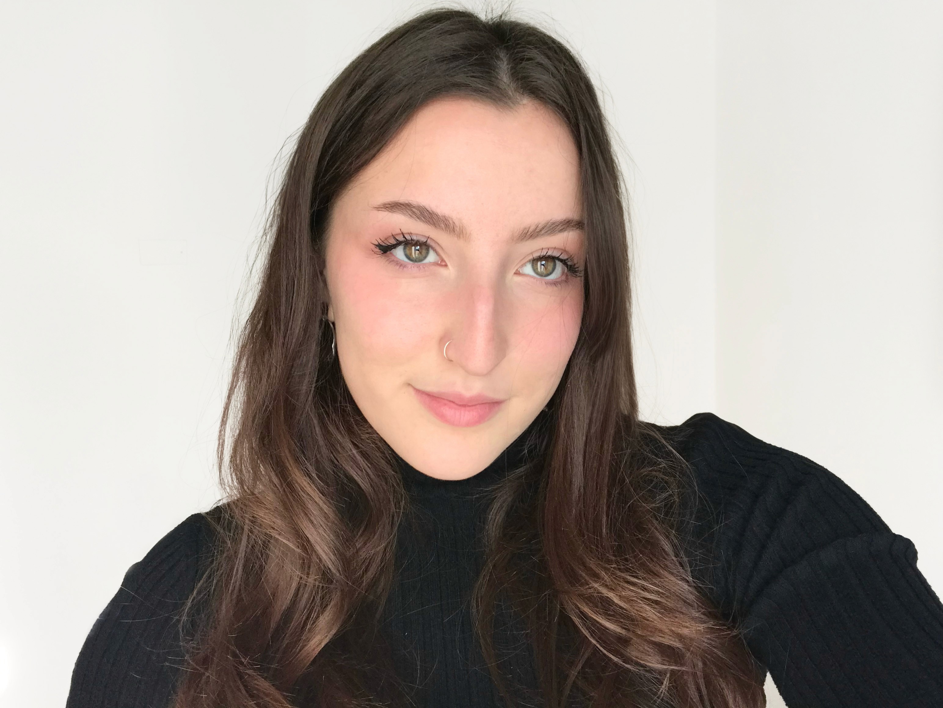 A thoughtful young person with dark hair gazes to the side, captured in soft black and white lighting.