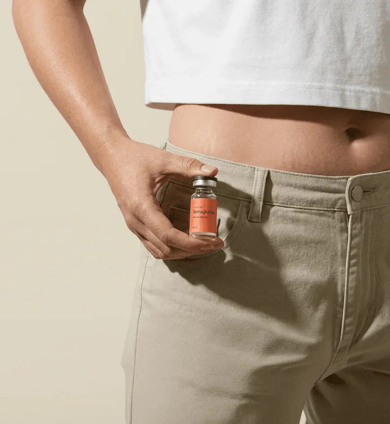 A person in a white T-shirt holding a small vial by their jeans pocket