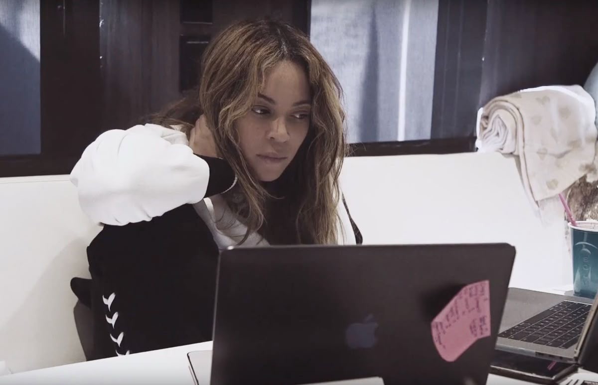 Modern home office setup with a monitor, ergonomic chair, keyboard, and indoor plants near a window with blinds.