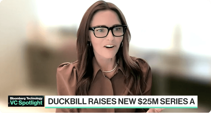 A woman with long, dark hair wearing glasses and a brown jacket, appearing to be in a professional setting for a news or media interview, with a text overlay indicating the topic is 'Duckbill raises new $25M Series A'.