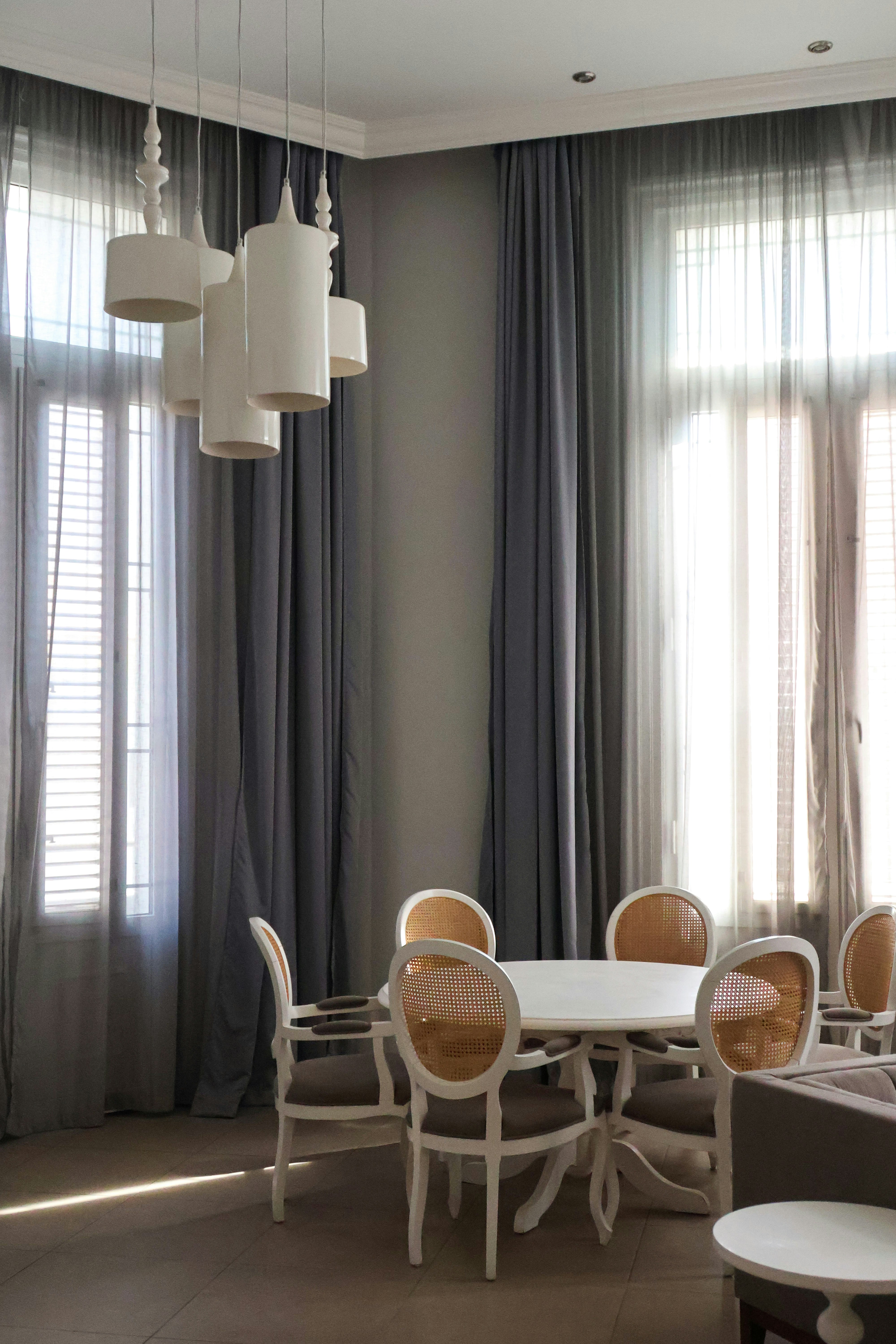 A modern dining room with chandelier and gray curtains.