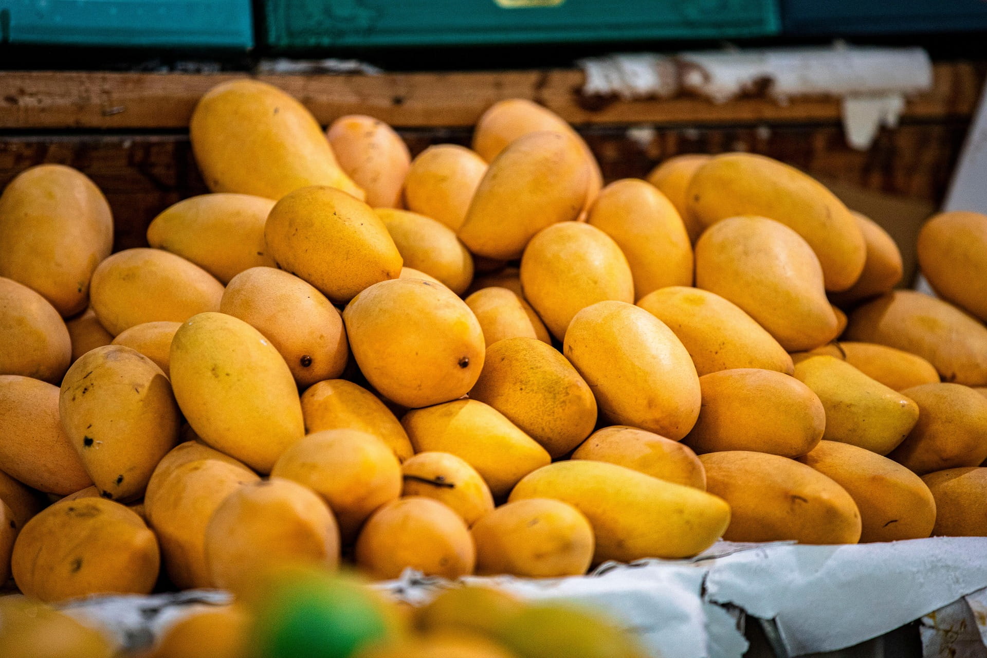 Mangos stacked on a table in a fruit market.