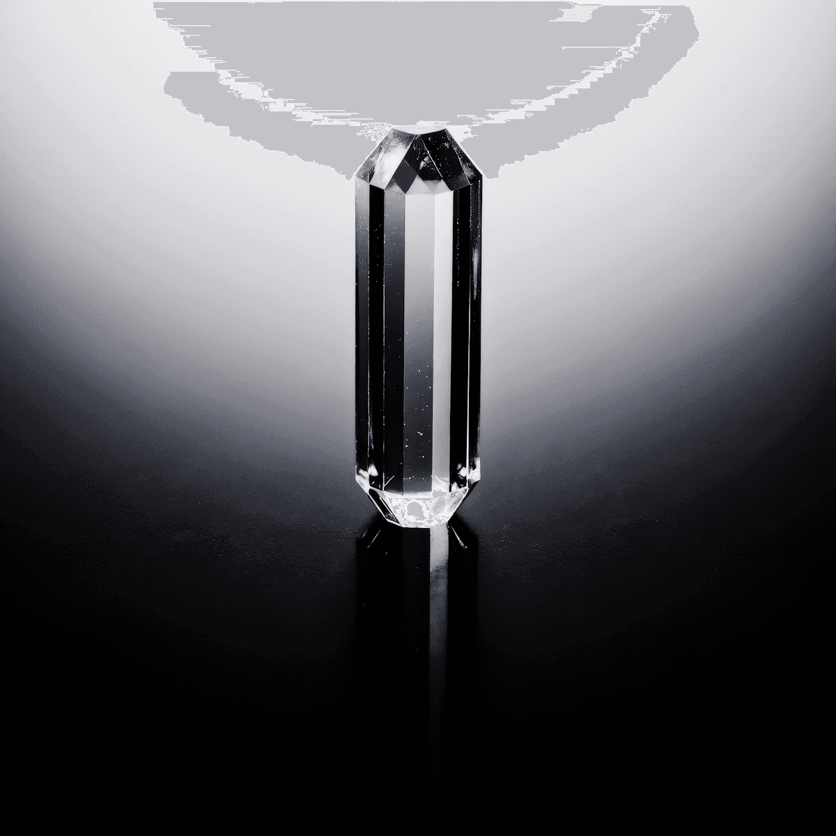 Clear faceted crystal prism standing upright on a reflective black surface, softly lit against a dark gradient background.