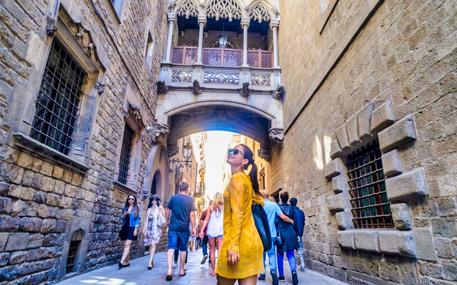 游客漫步在巴塞罗那叹息桥下的哥特区街道上。