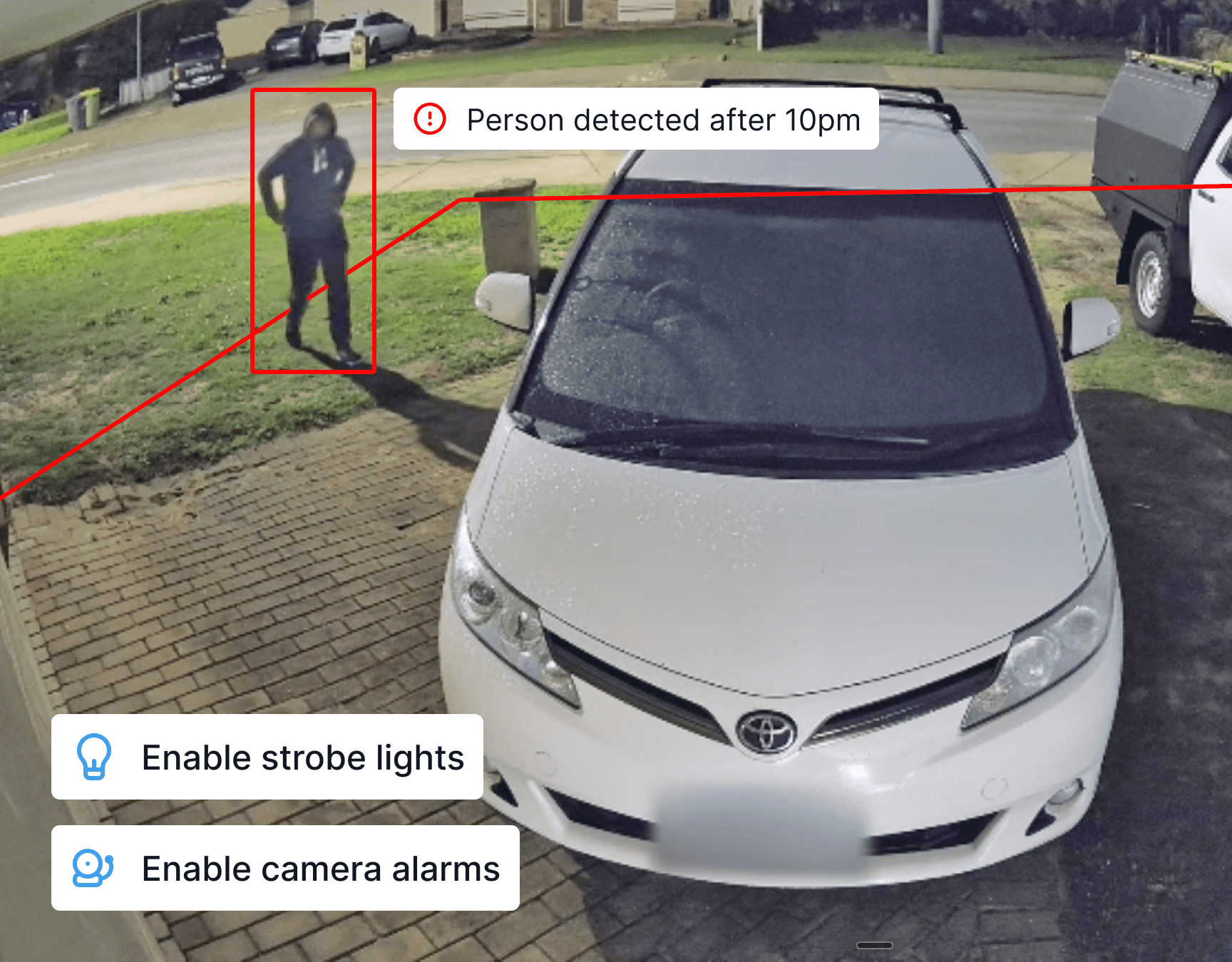 Man in hoodie approaching someone's driveway at night and tripping the security system