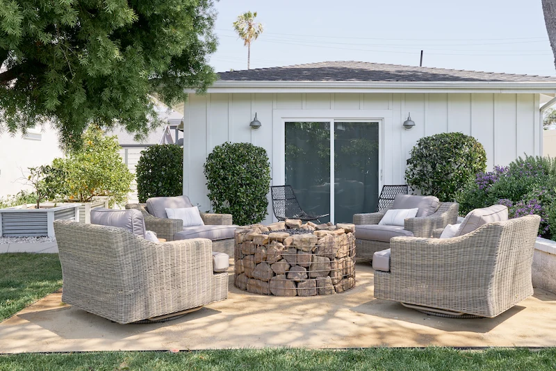 Outdoor firepit and seating area with dirt floor and surrounding grass. Modern Farmhouse patio. Photo by Todd Huge.