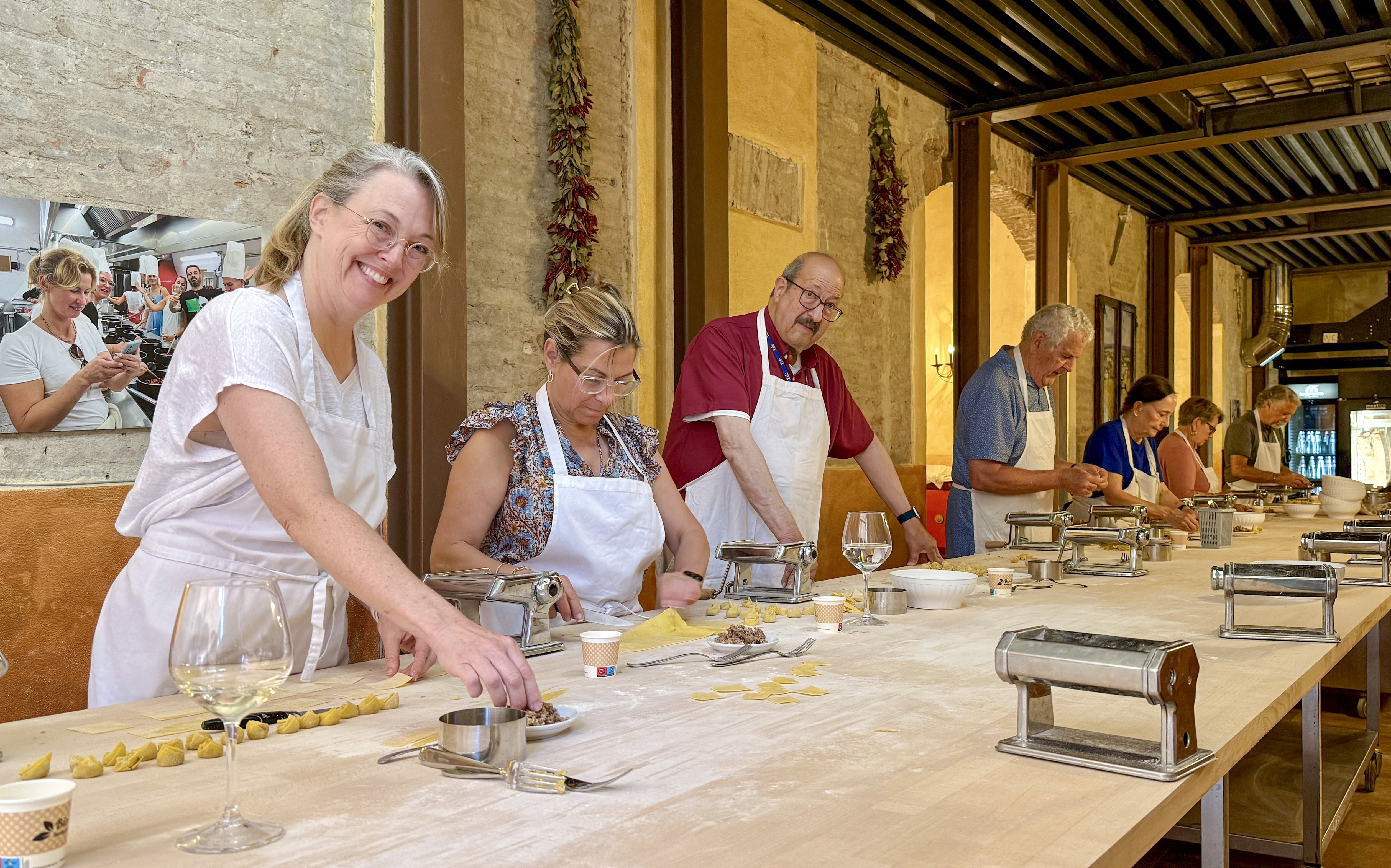 People in Siena cooking class making pasta at a long table with pasta machines.