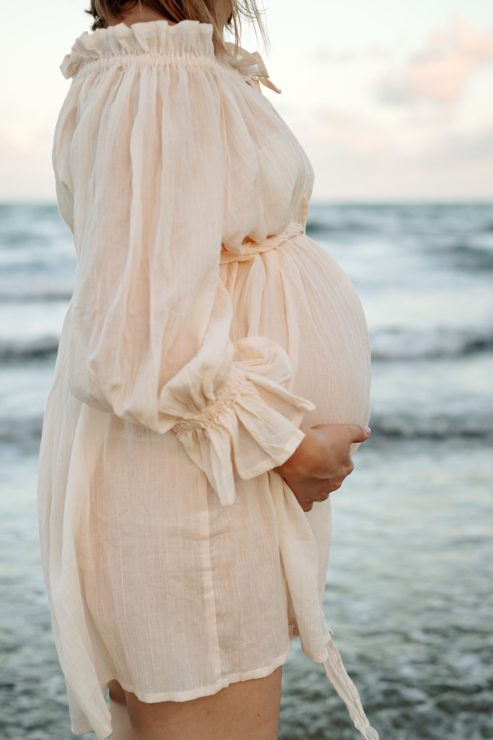 Serene sunset maternity portrait of pregnant mother standing by the ocean during a Mackay beach maternity session.