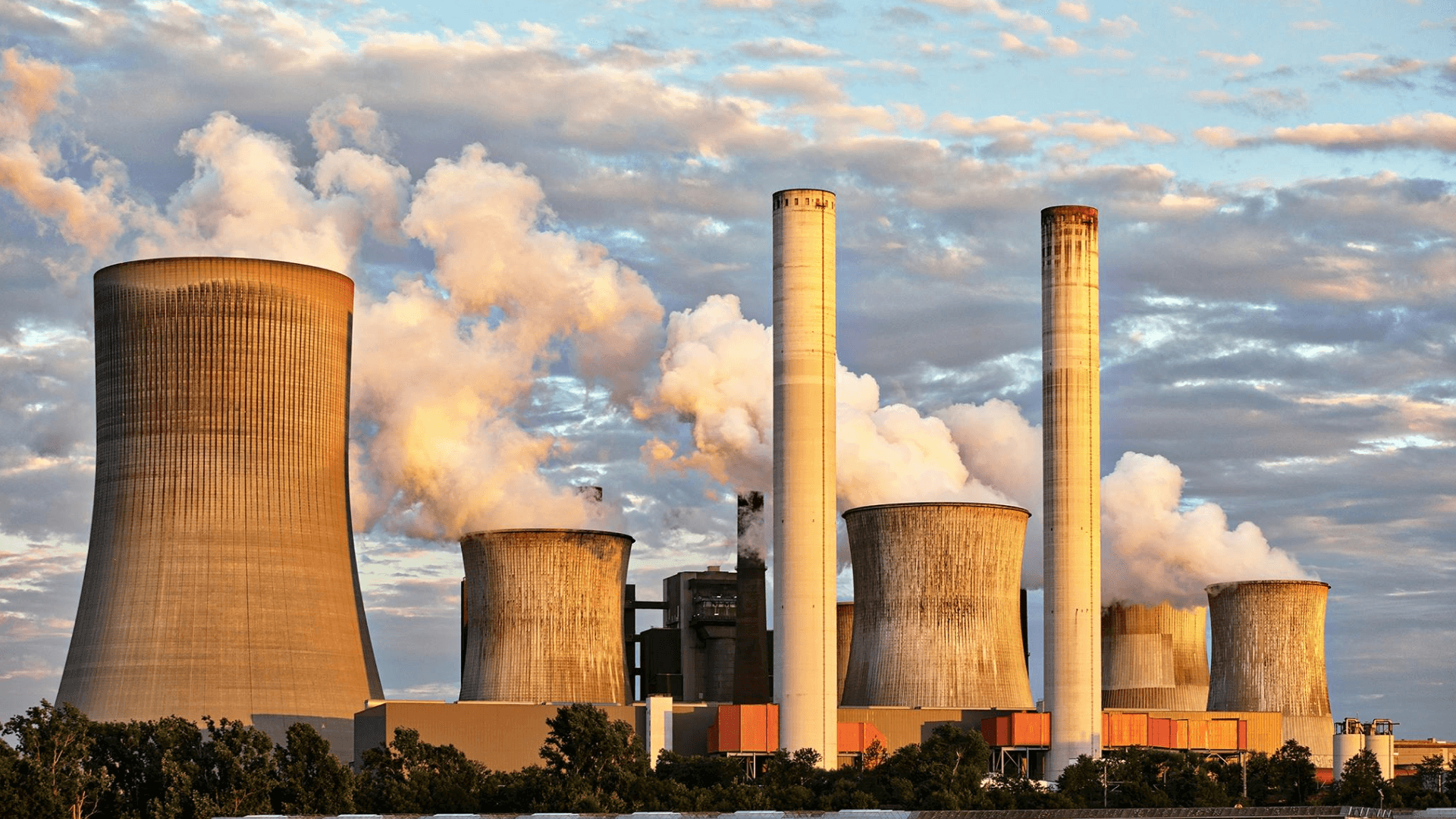 Fossil fuel power plant with cooling towers releasing steam, representing the role of traditional energy in the transition toward cleaner renewables
