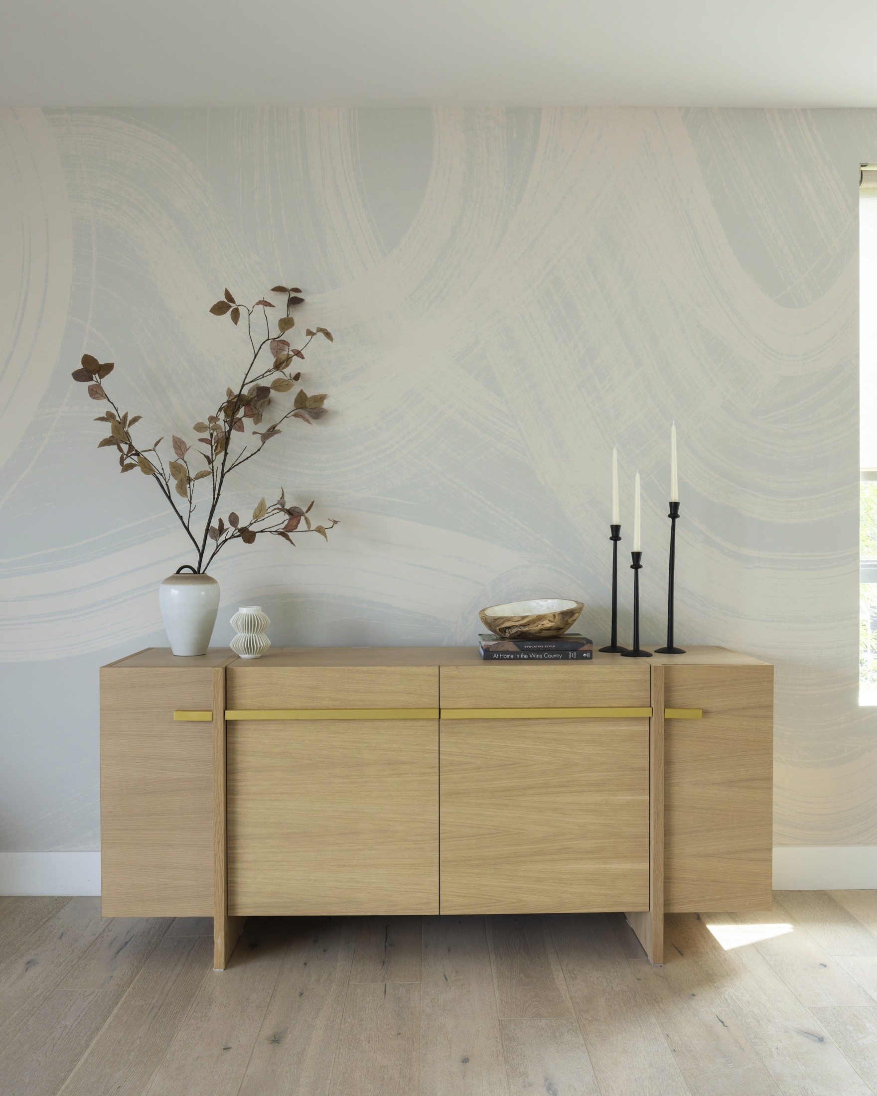 Large credenza with tapers, decorative books, and ceramic vases with large branches