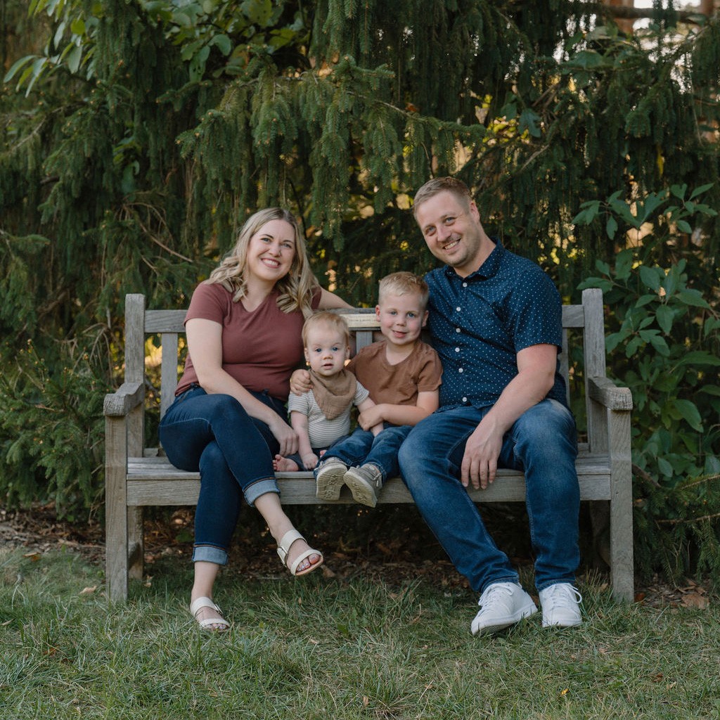 A person in a winter coat and furry hat walking along a snow-covered path through a forest of frosted trees.