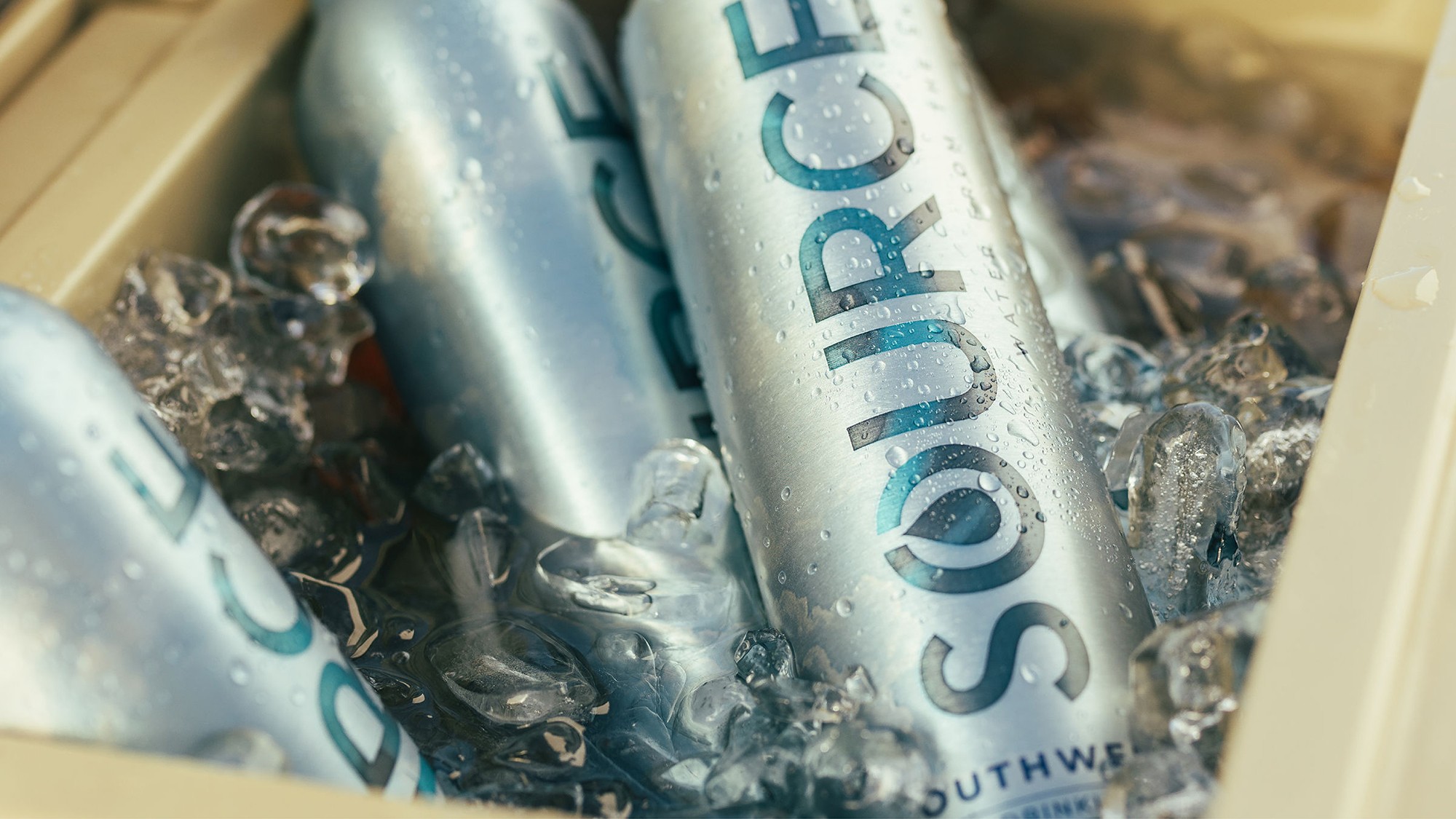 Aluminium water cans resting in ice, with condensation visible on the surface.