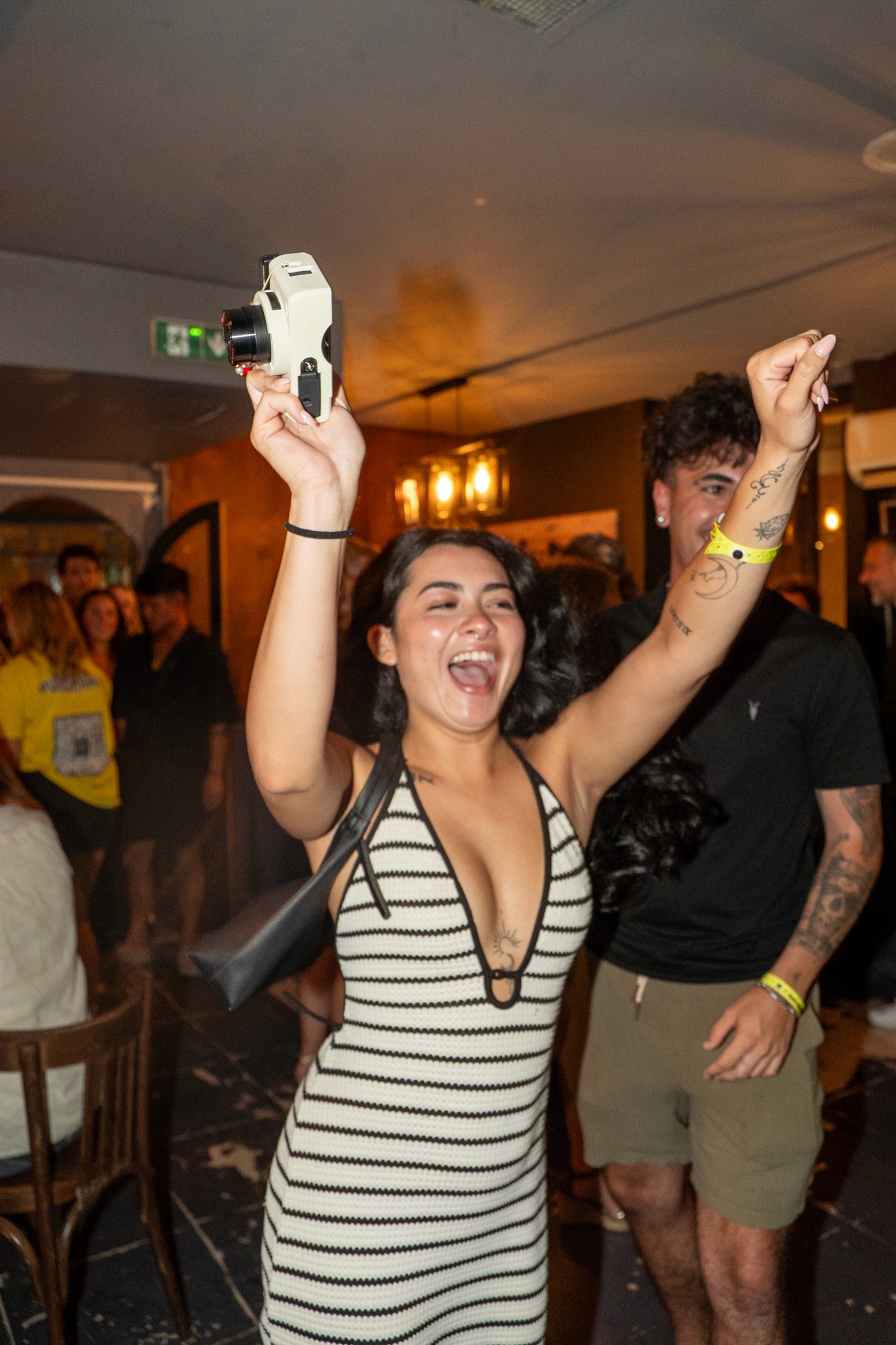Young woman celebrating with arms raised during a bar crawl in Nice capturing pure excitement confidence and high energy party vibes inside a lively nightlife venue on the French Riviera