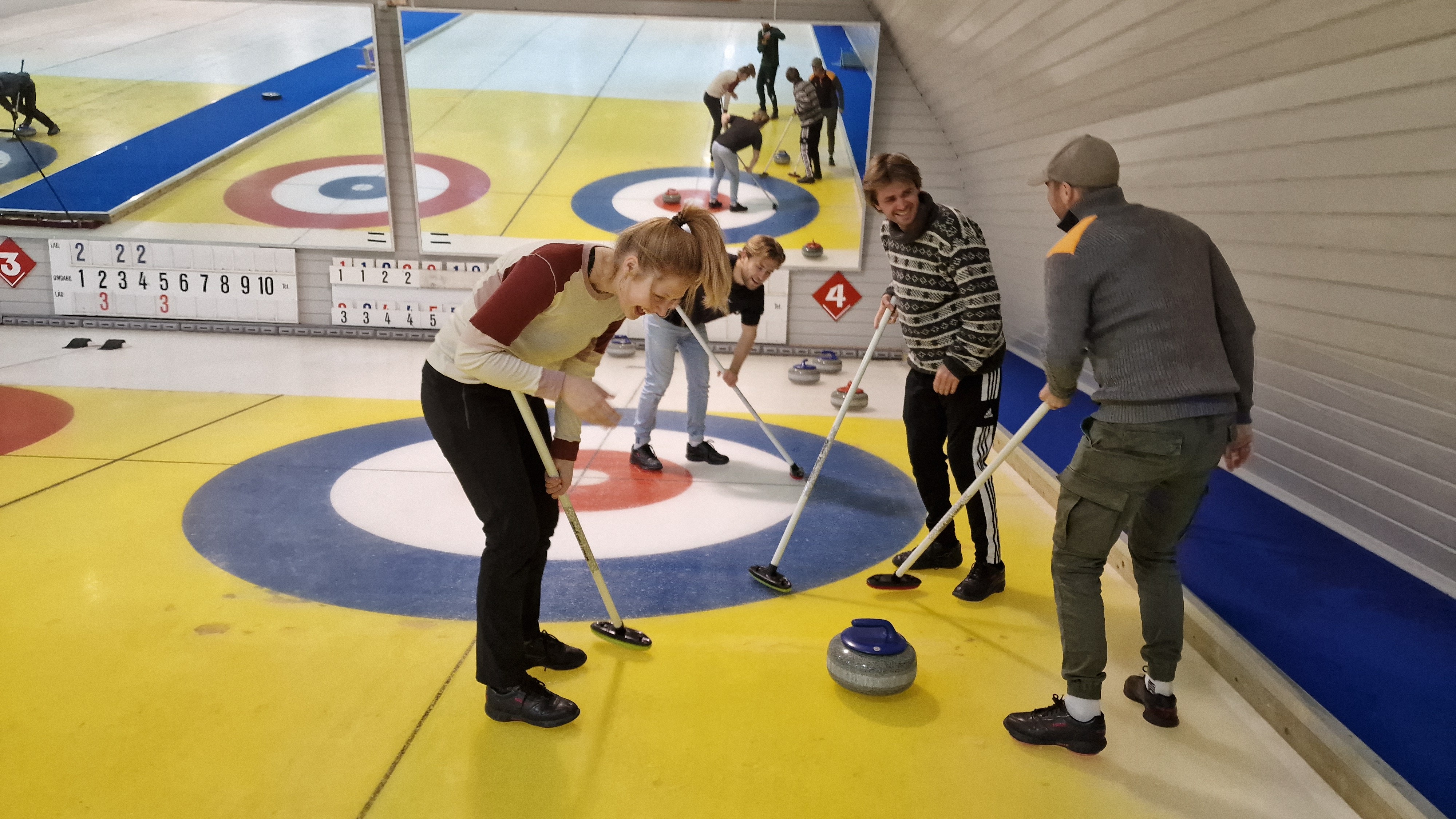 The trainees from Aneo are at a curling rink playing curling together.
