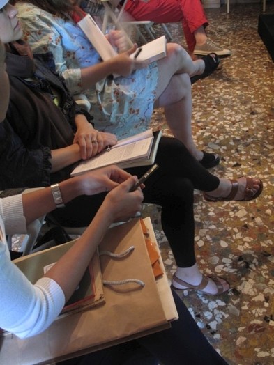 A group of people sitting on chairs with books and notes on their lap.